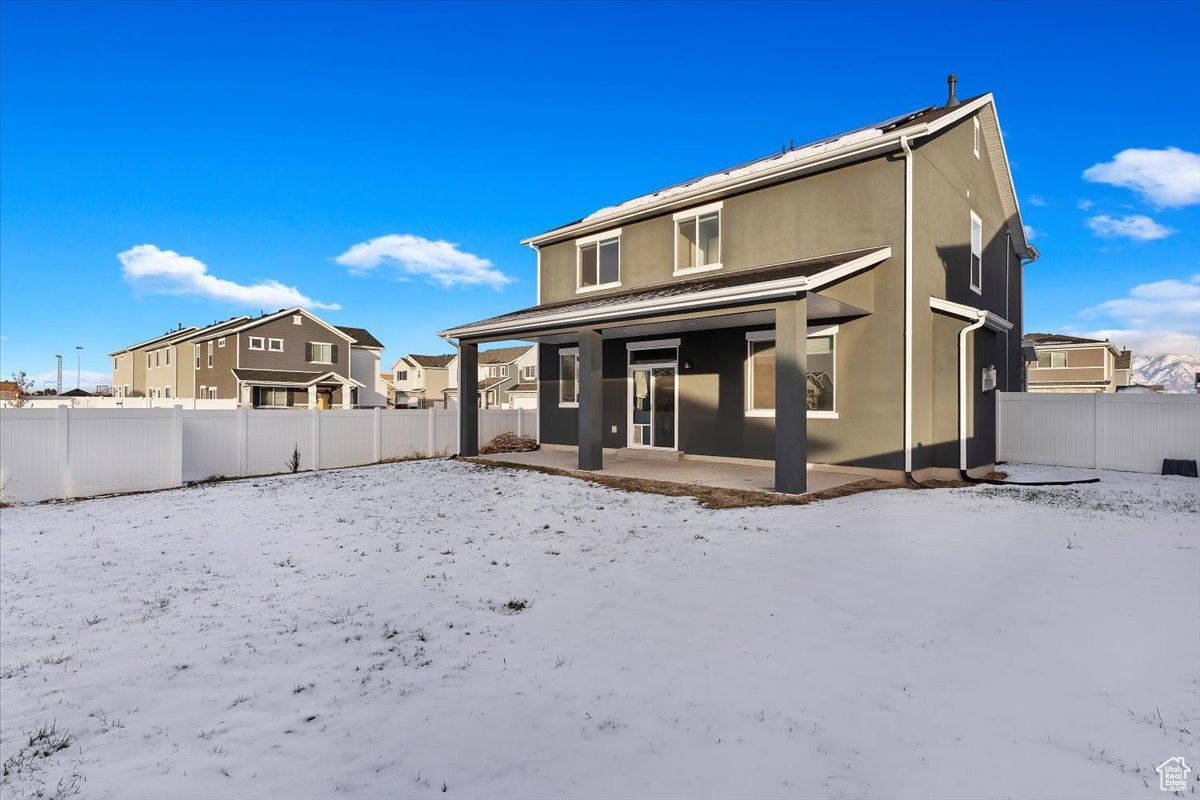 Snow covered back of property featuring a patio area