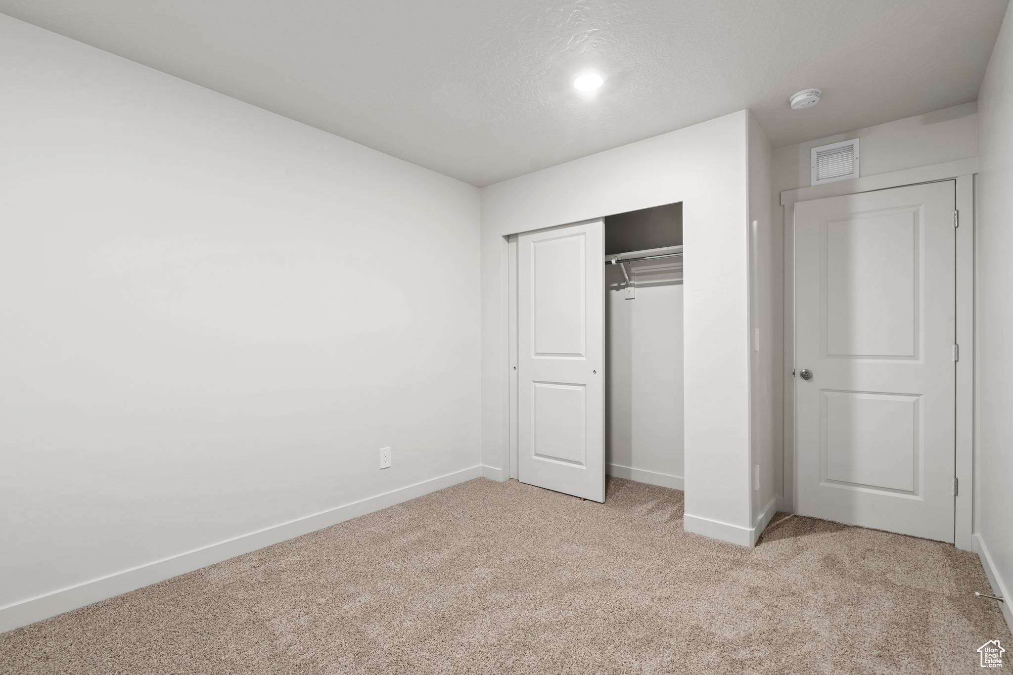 Unfurnished bedroom featuring light carpet and a closet