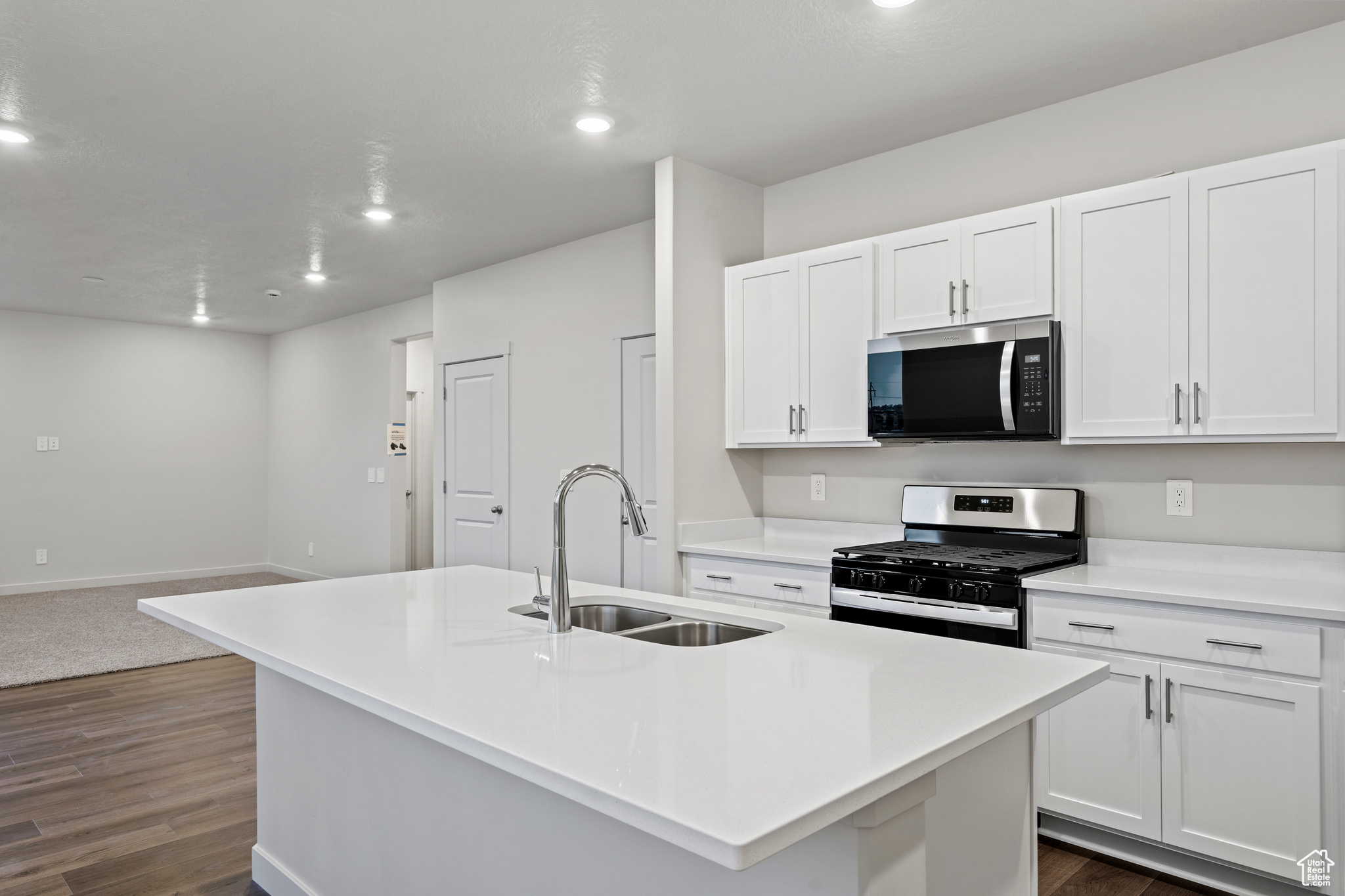 Kitchen with white cabinetry, stainless steel appliances, sink, and a kitchen island with sink