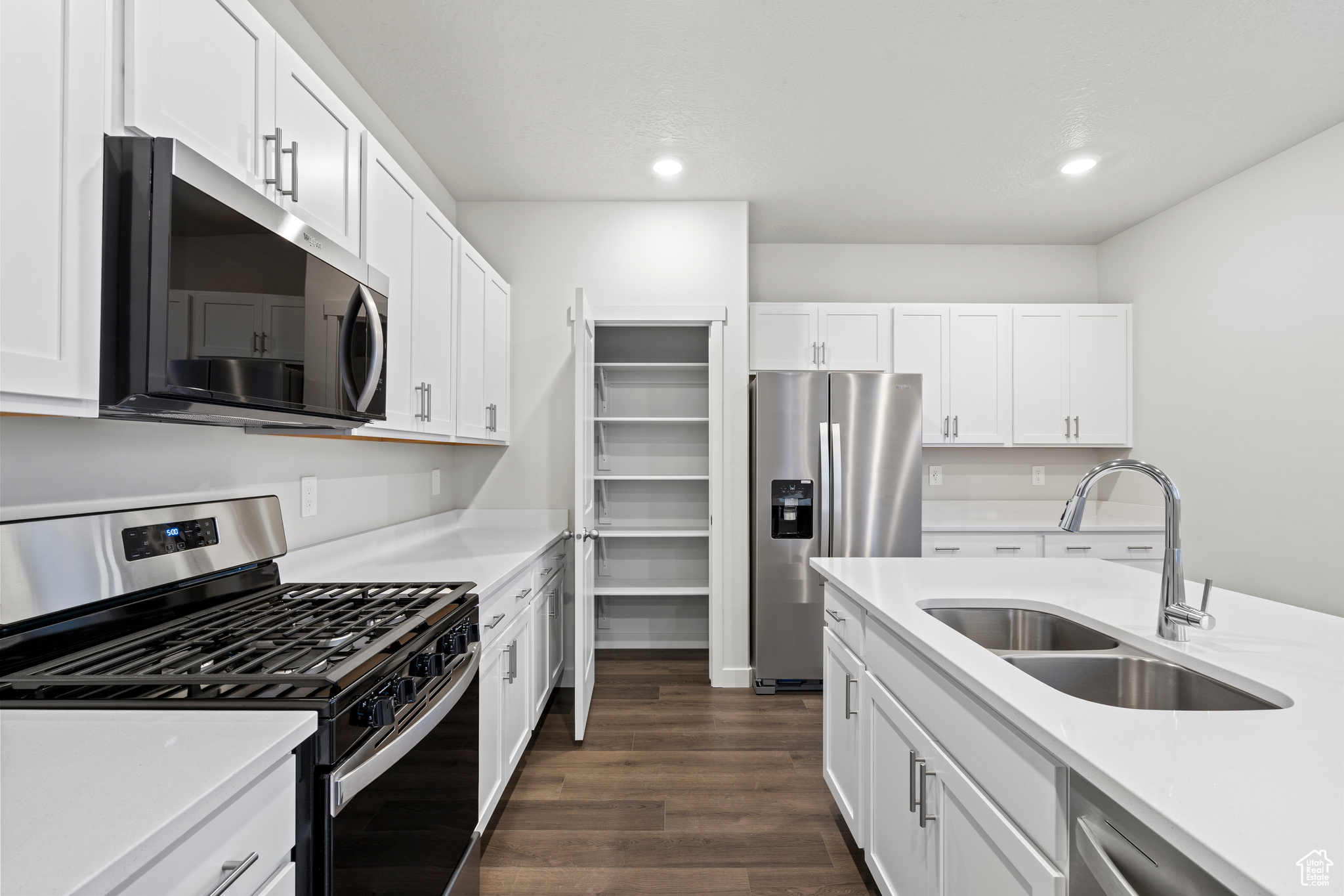 Kitchen with white cabinetry, sink, dark hardwood / wood-style flooring, and appliances with stainless steel finishes