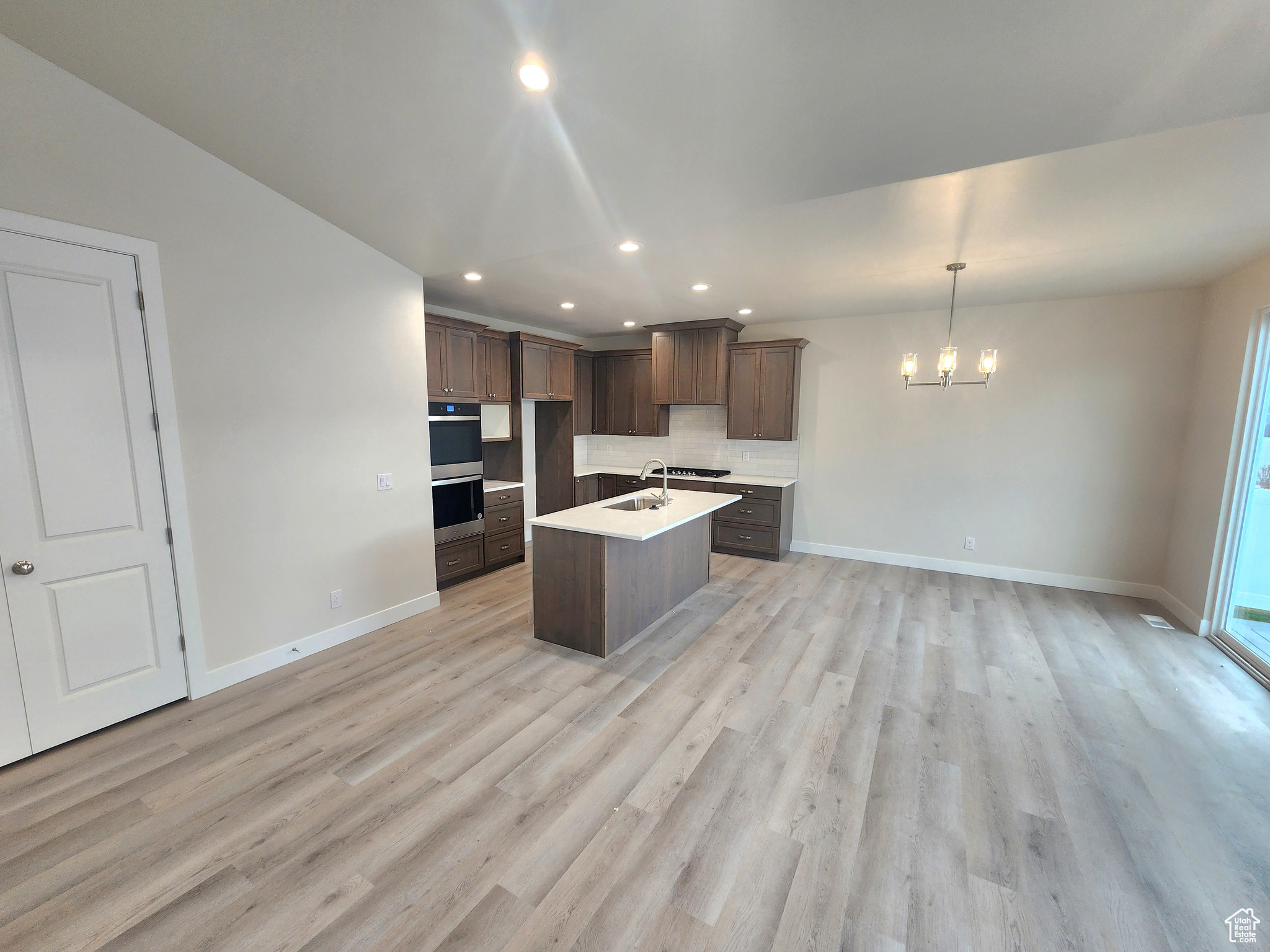 Kitchen featuring a chandelier, an island with sink, light hardwood / wood-style floors, and sink