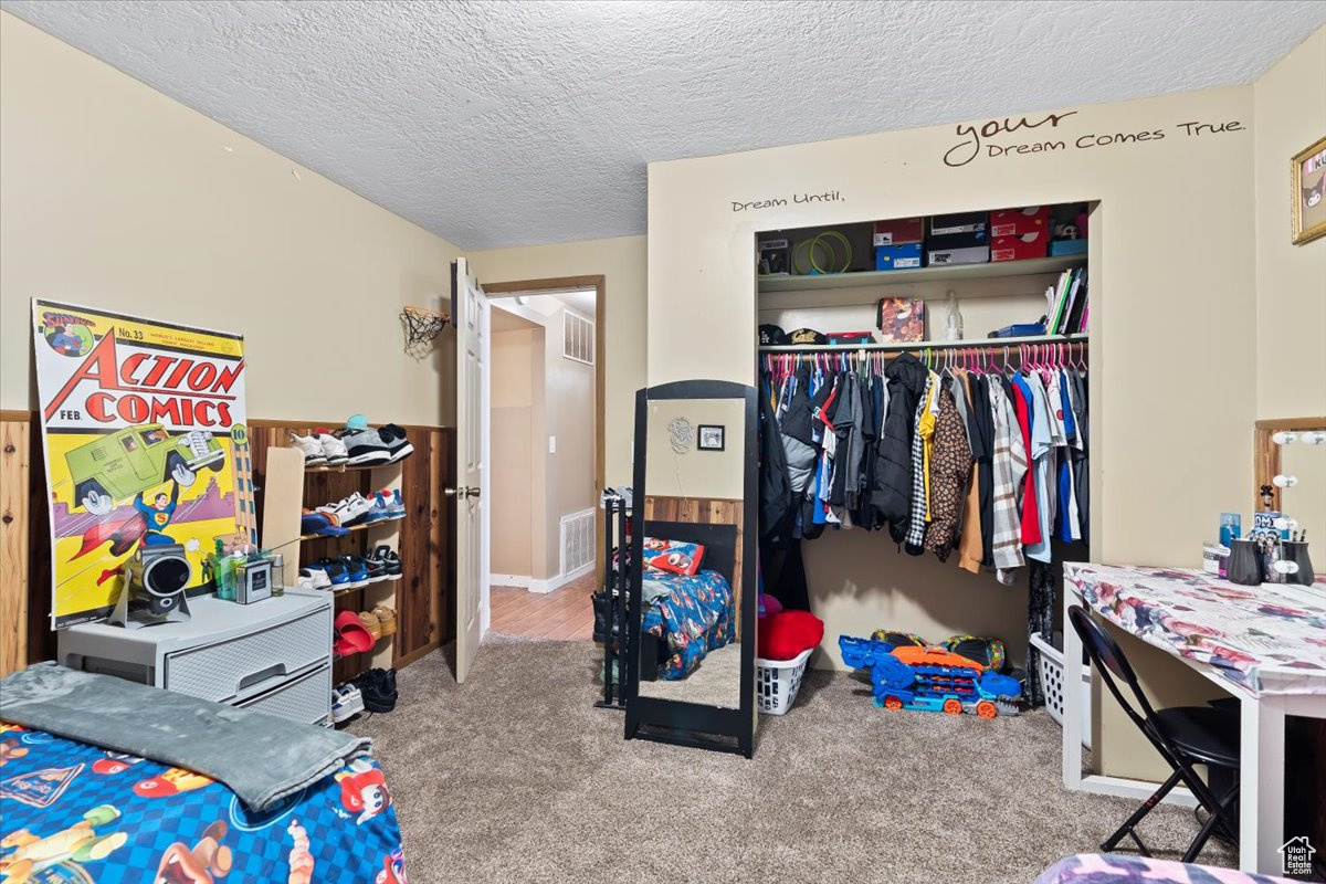 Bedroom with carpet flooring, a textured ceiling, and a closet