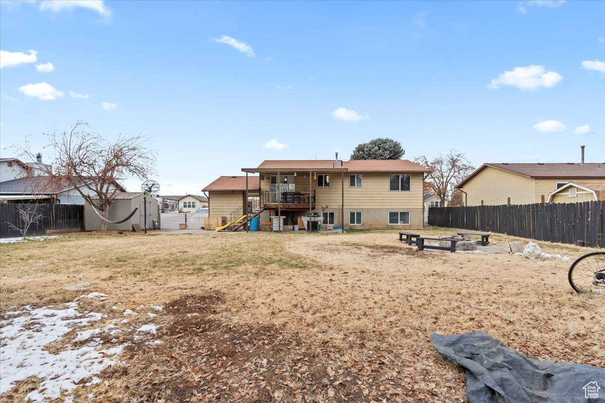 Rear view of property featuring a fire pit, a deck, and a lawn