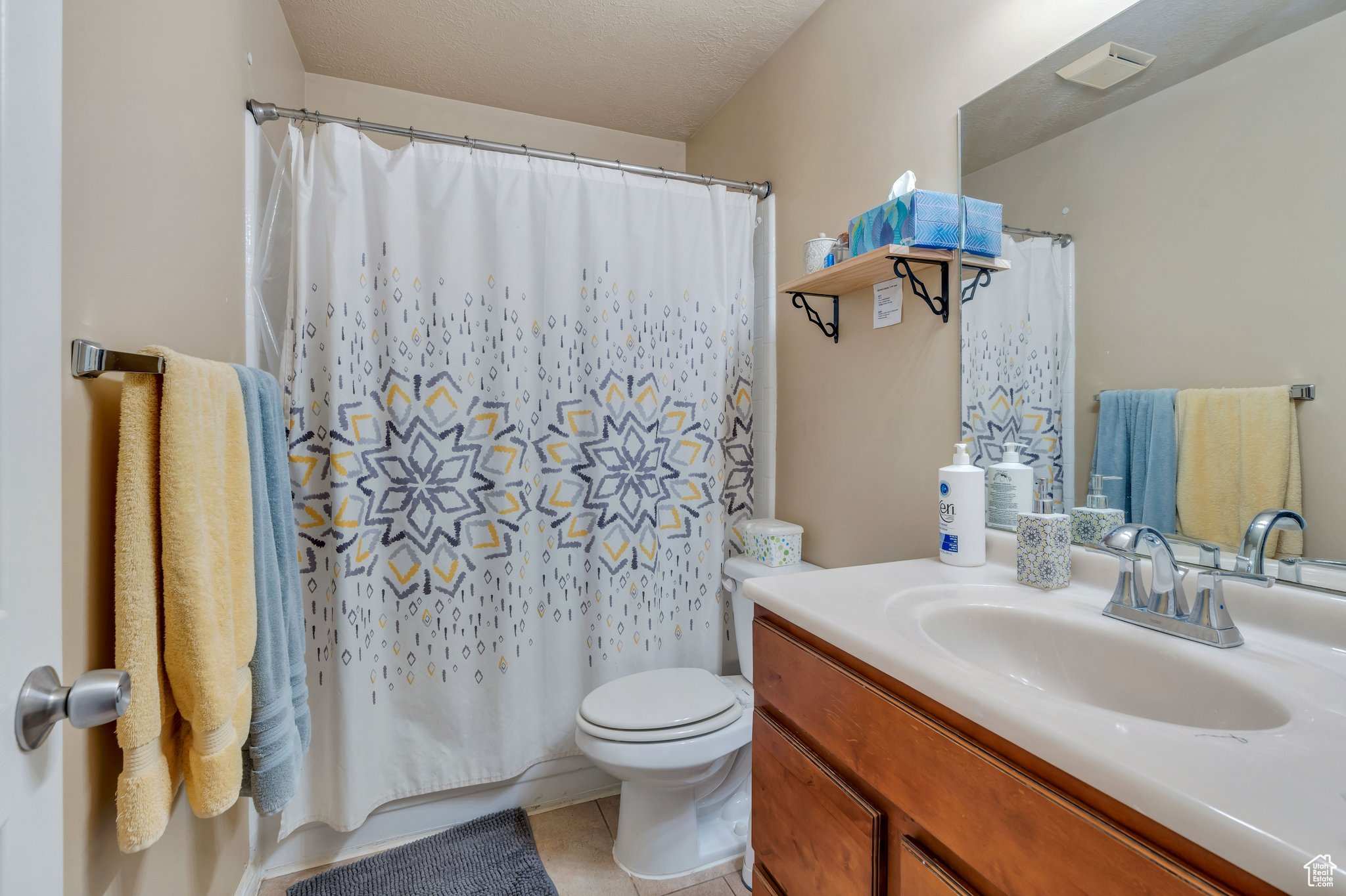 Bathroom with tile patterned flooring, vanity, toilet, and a textured ceiling