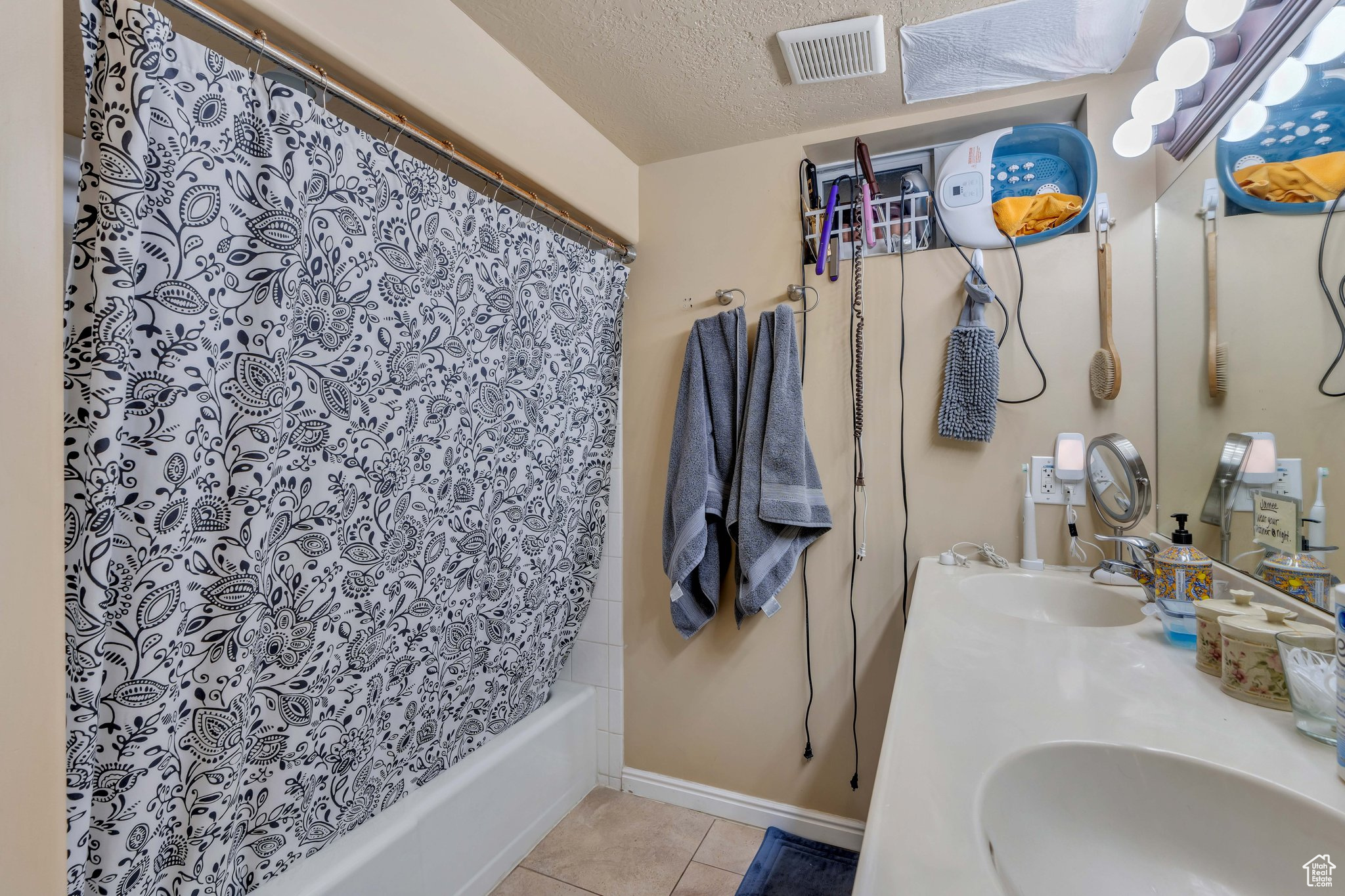 Bathroom featuring vanity, a textured ceiling, tile patterned floors, and shower / bath combo with shower curtain