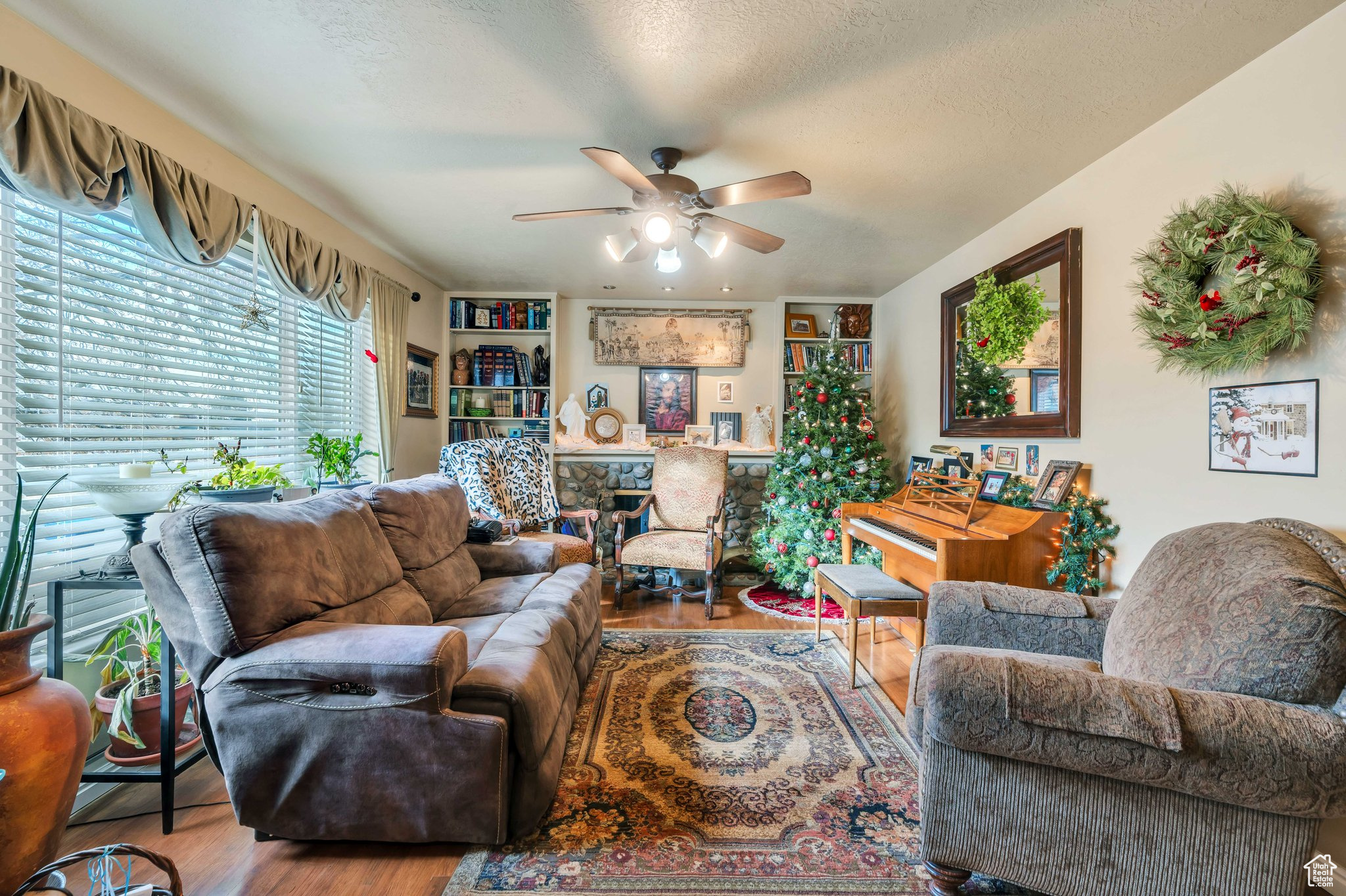 Living room with ceiling fan, a textured ceiling, and hardwood / wood-style flooring