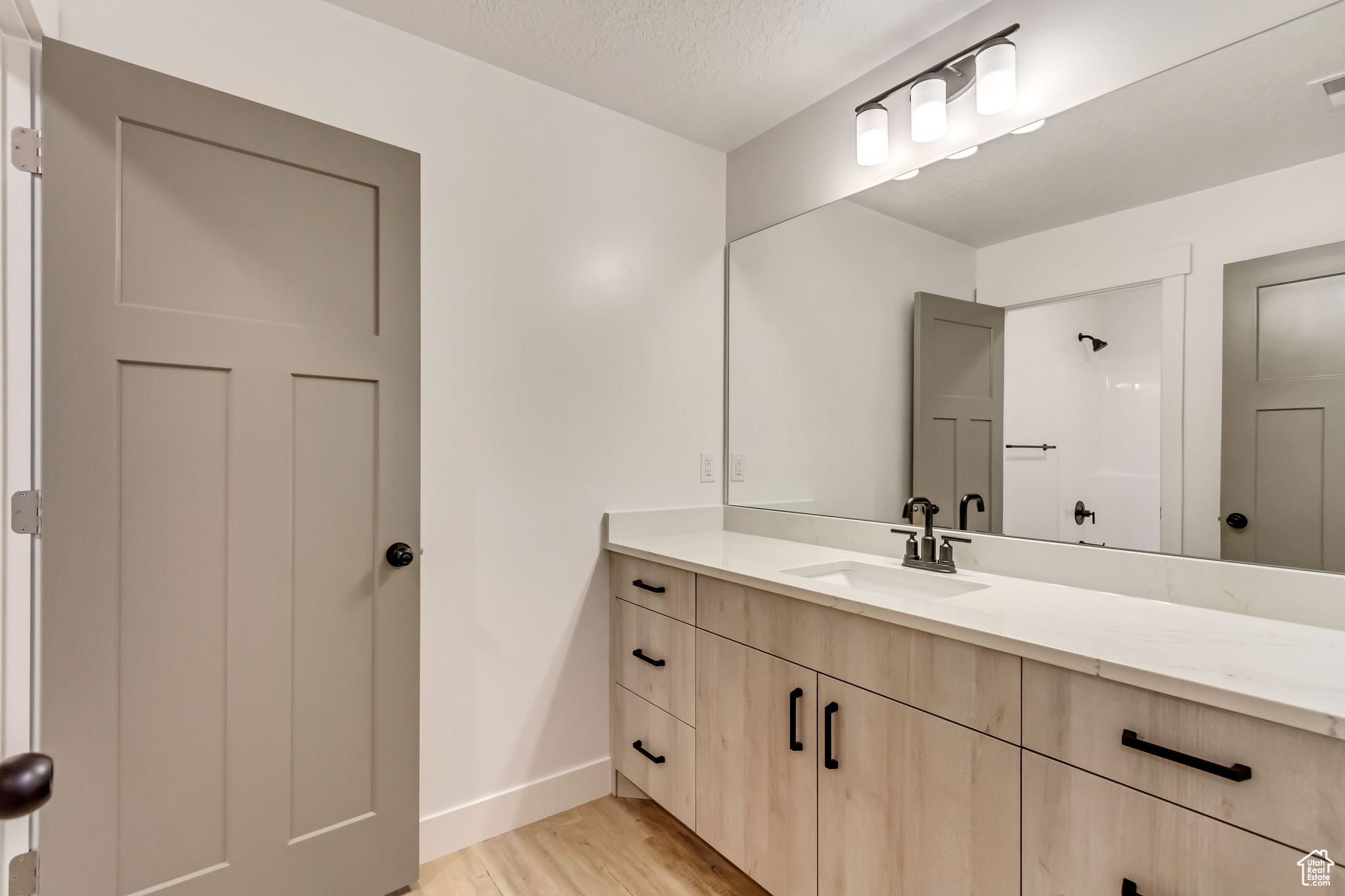 Bathroom with hardwood / wood-style flooring, vanity, and a textured ceiling