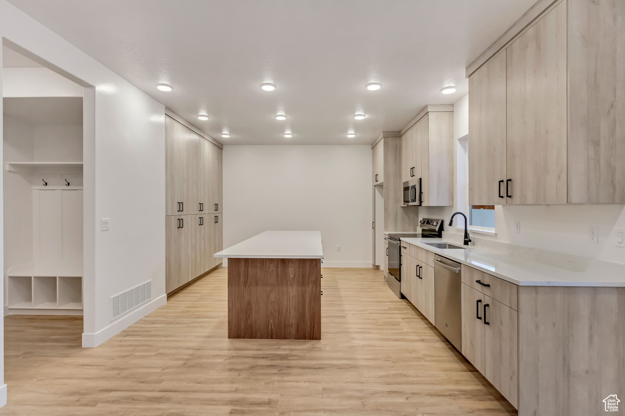 Kitchen with a center island, sink, light brown cabinetry, appliances with stainless steel finishes, and light hardwood / wood-style floors