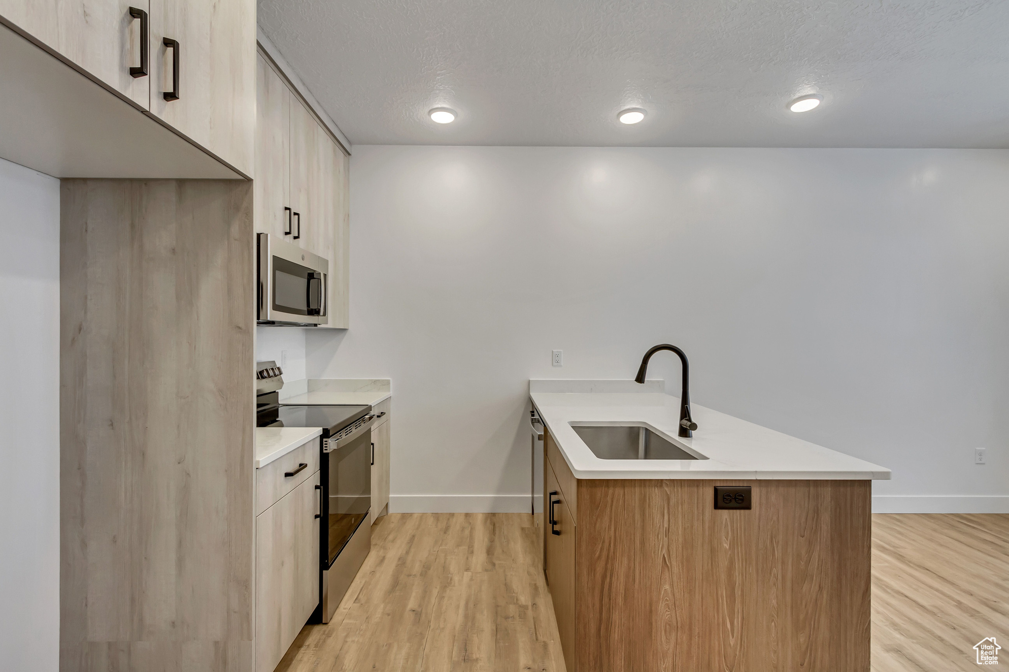 Kitchen featuring sink, stainless steel appliances, light brown cabinetry, and light hardwood / wood-style flooring