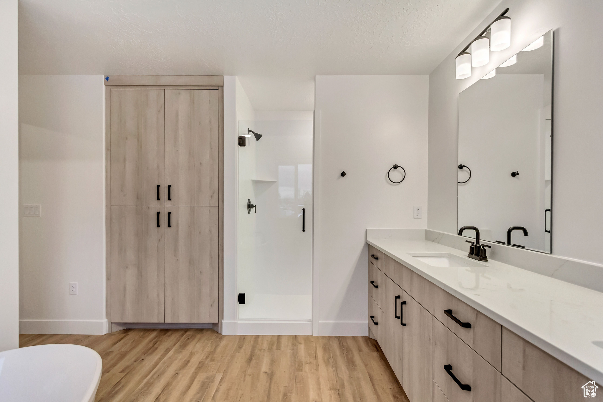 Bathroom with vanity, wood-type flooring, a textured ceiling, and walk in shower