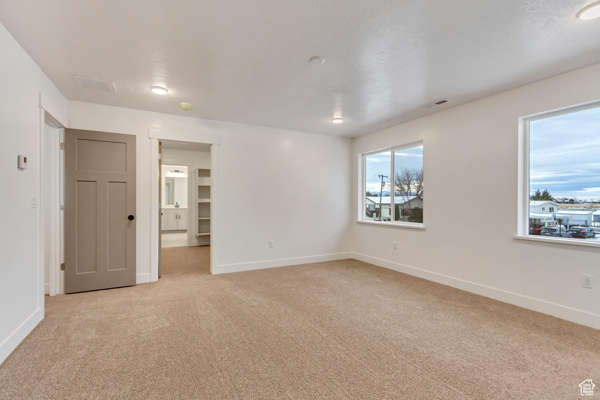 Empty room with light colored carpet and a textured ceiling