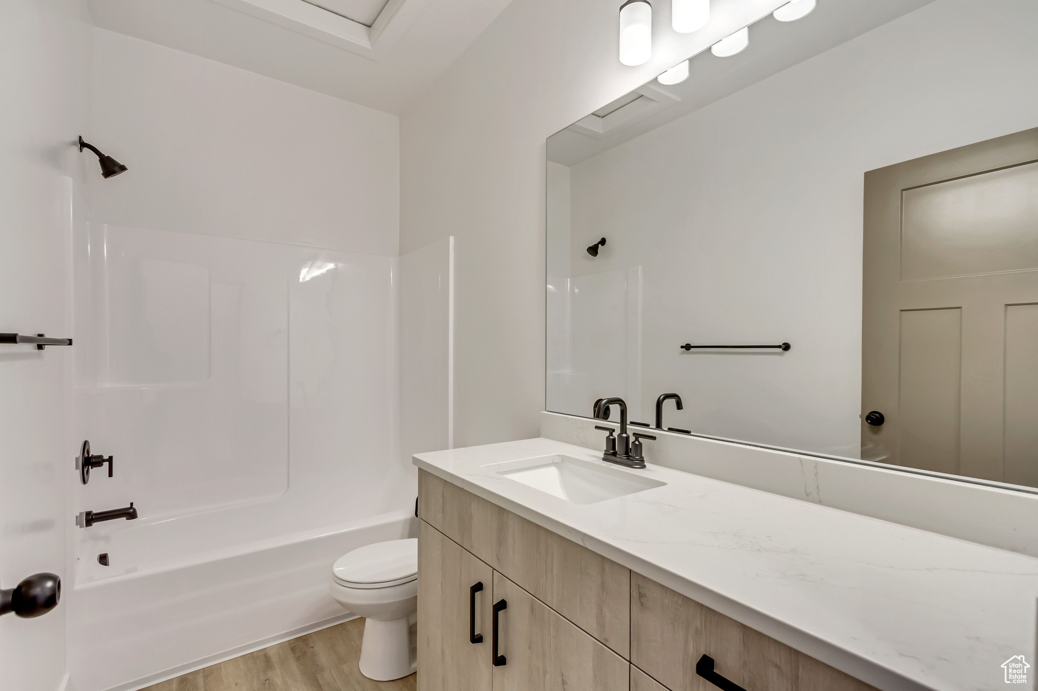 Full bathroom featuring vanity, wood-type flooring,  shower combination, and toilet