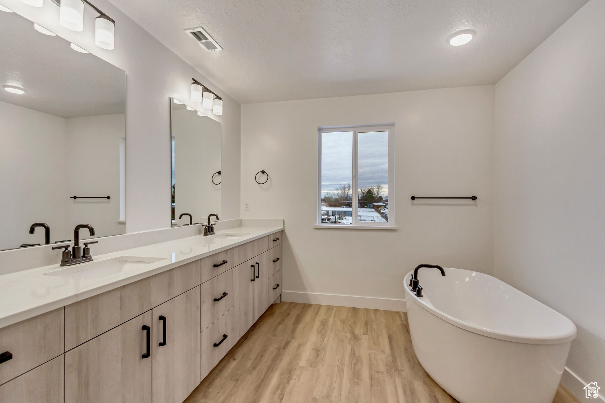 Bathroom featuring a tub to relax in, vanity, and hardwood / wood-style flooring