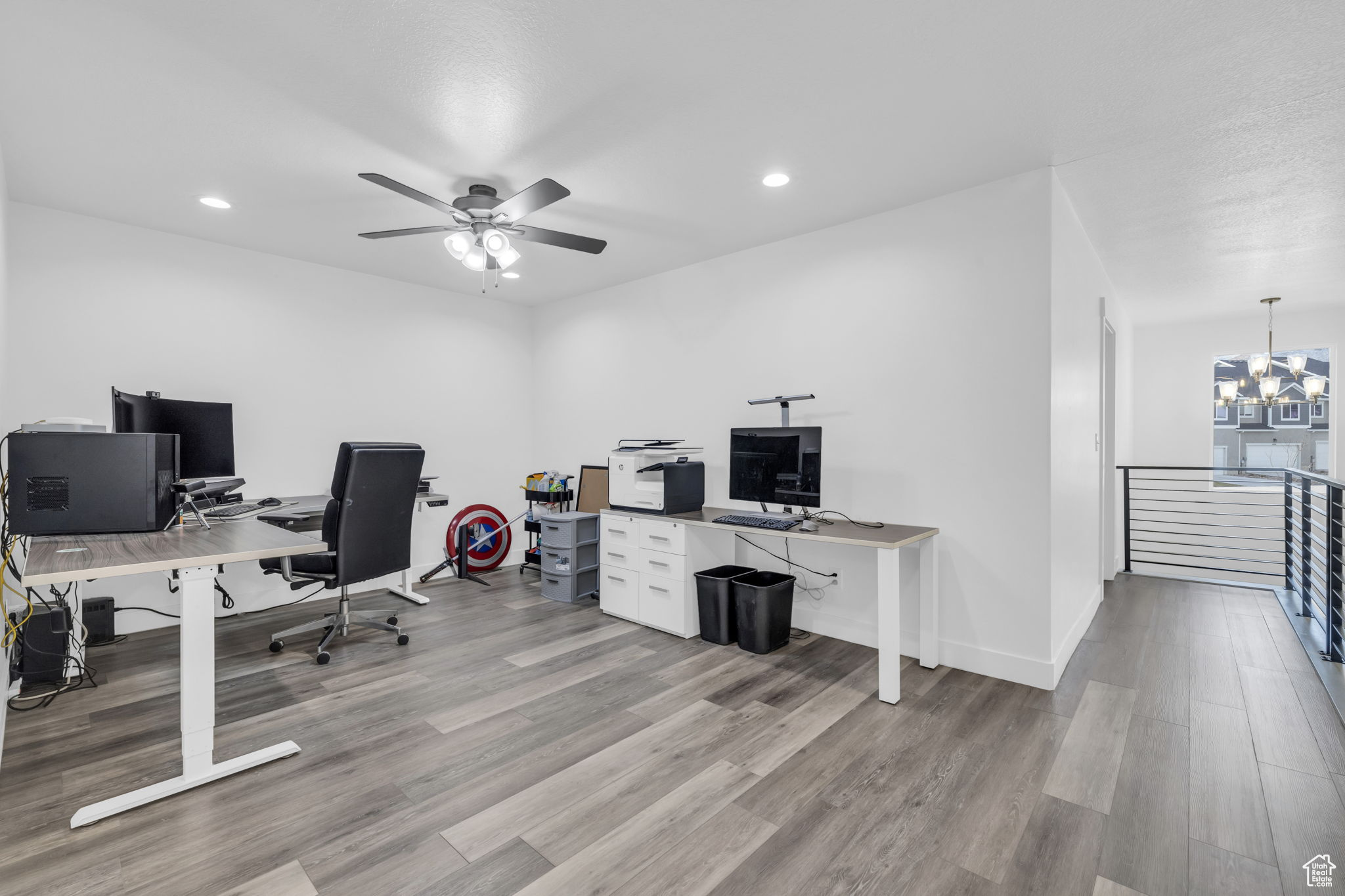 Home office featuring ceiling fan with notable chandelier and light wood-type flooring