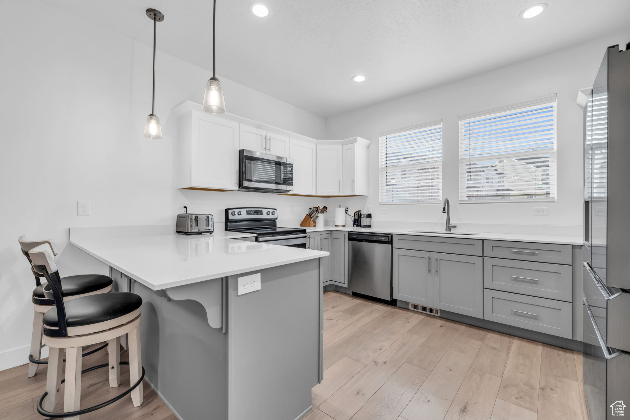 Kitchen with sink, stainless steel appliances, a kitchen breakfast bar, kitchen peninsula, and decorative light fixtures