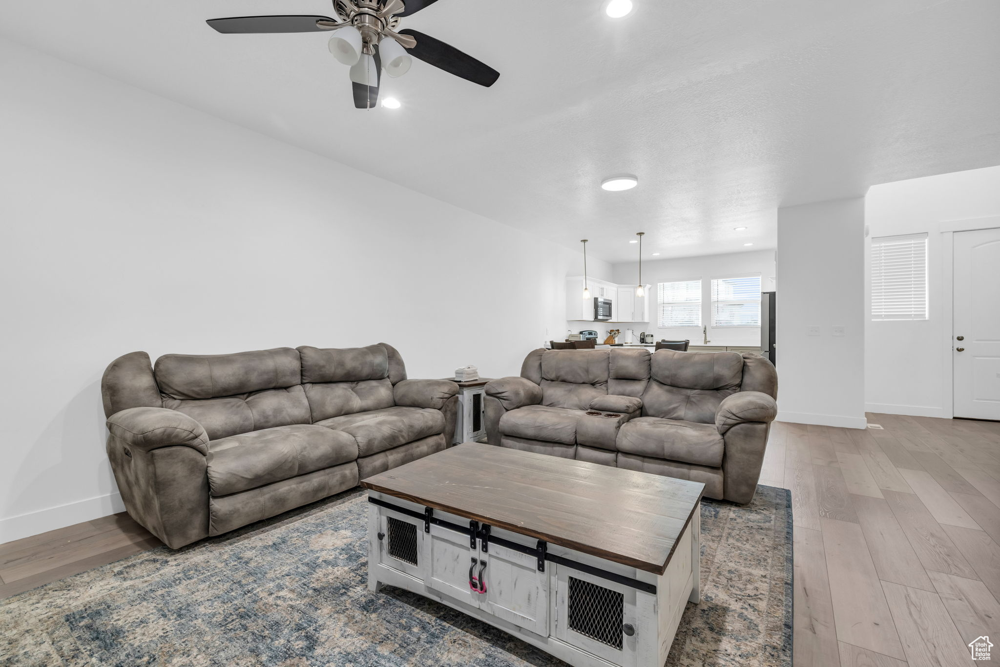 Living room with ceiling fan and light hardwood / wood-style floors