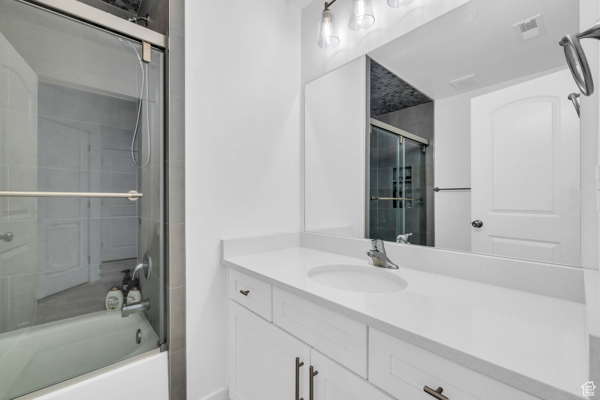 Bathroom featuring vanity and bath / shower combo with glass door