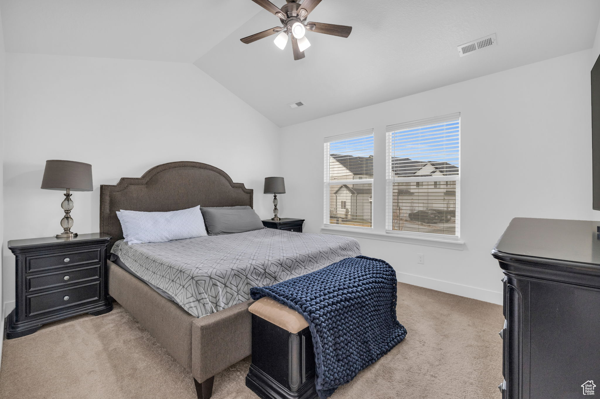 Carpeted bedroom featuring vaulted ceiling and ceiling fan