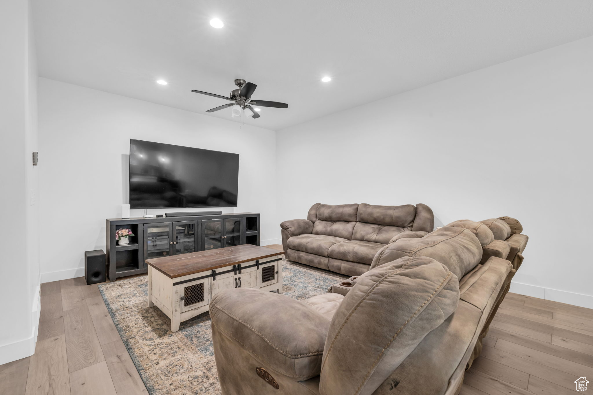 Living room with ceiling fan and light hardwood / wood-style floors