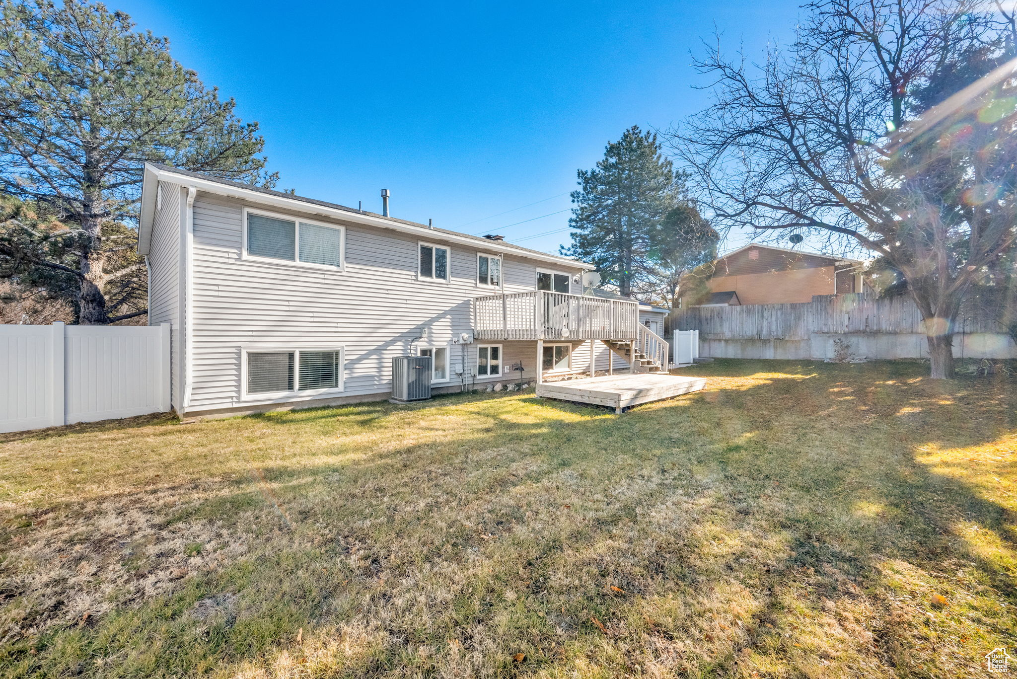 Back of property featuring central AC, a deck, and a lawn