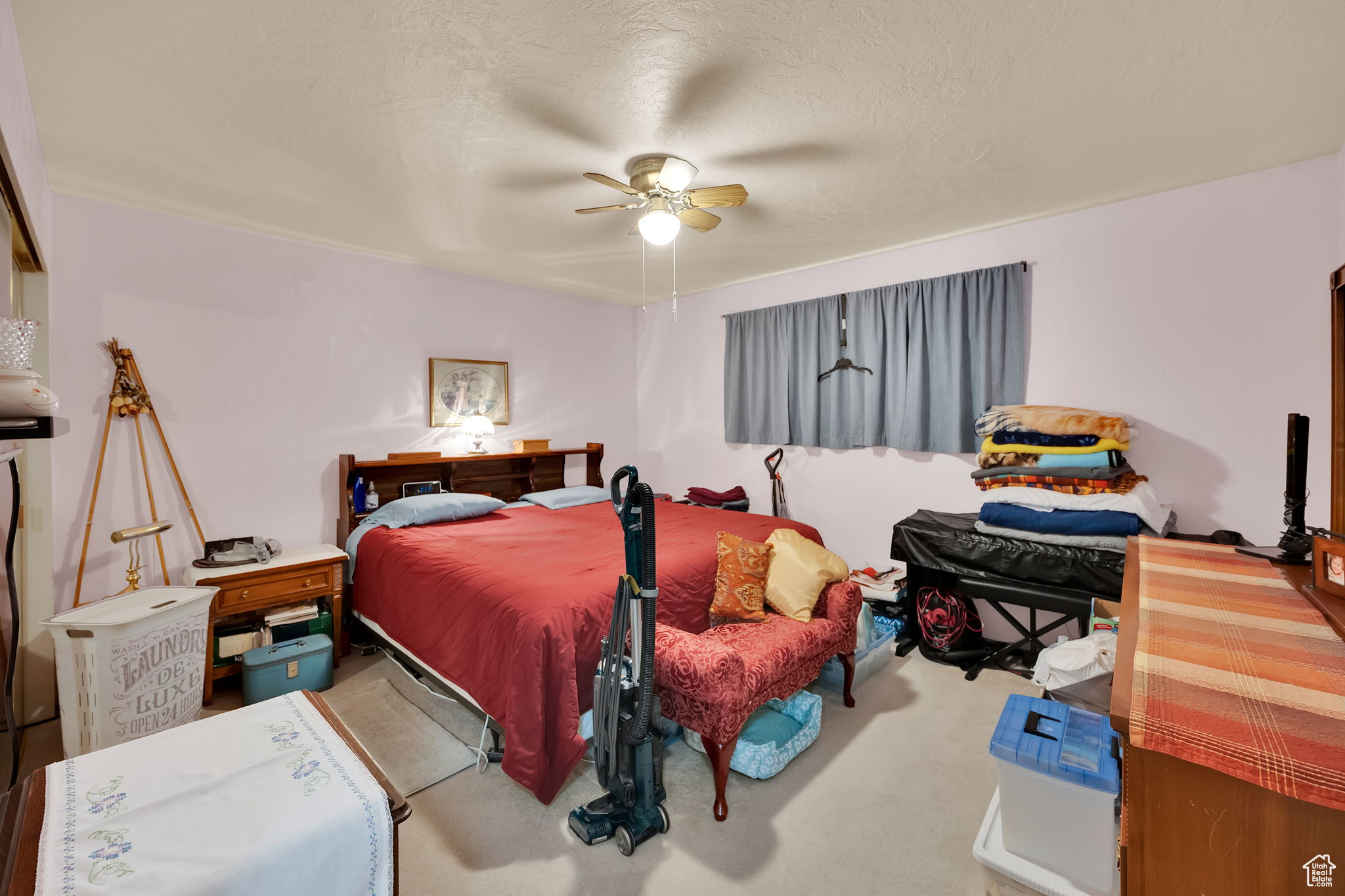 Carpeted bedroom featuring ceiling fan and a textured ceiling