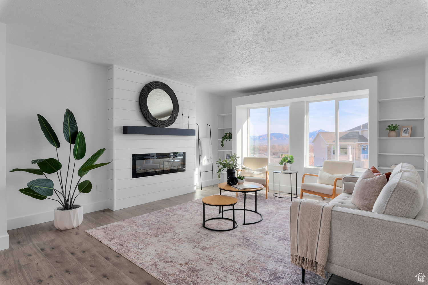 Living room with a mountain view, a textured ceiling, a large fireplace, and light hardwood / wood-style flooring