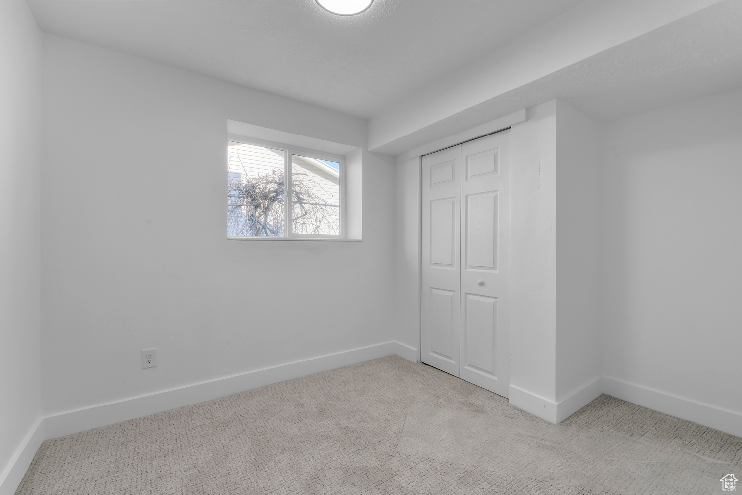 Unfurnished bedroom featuring a closet and light colored carpet