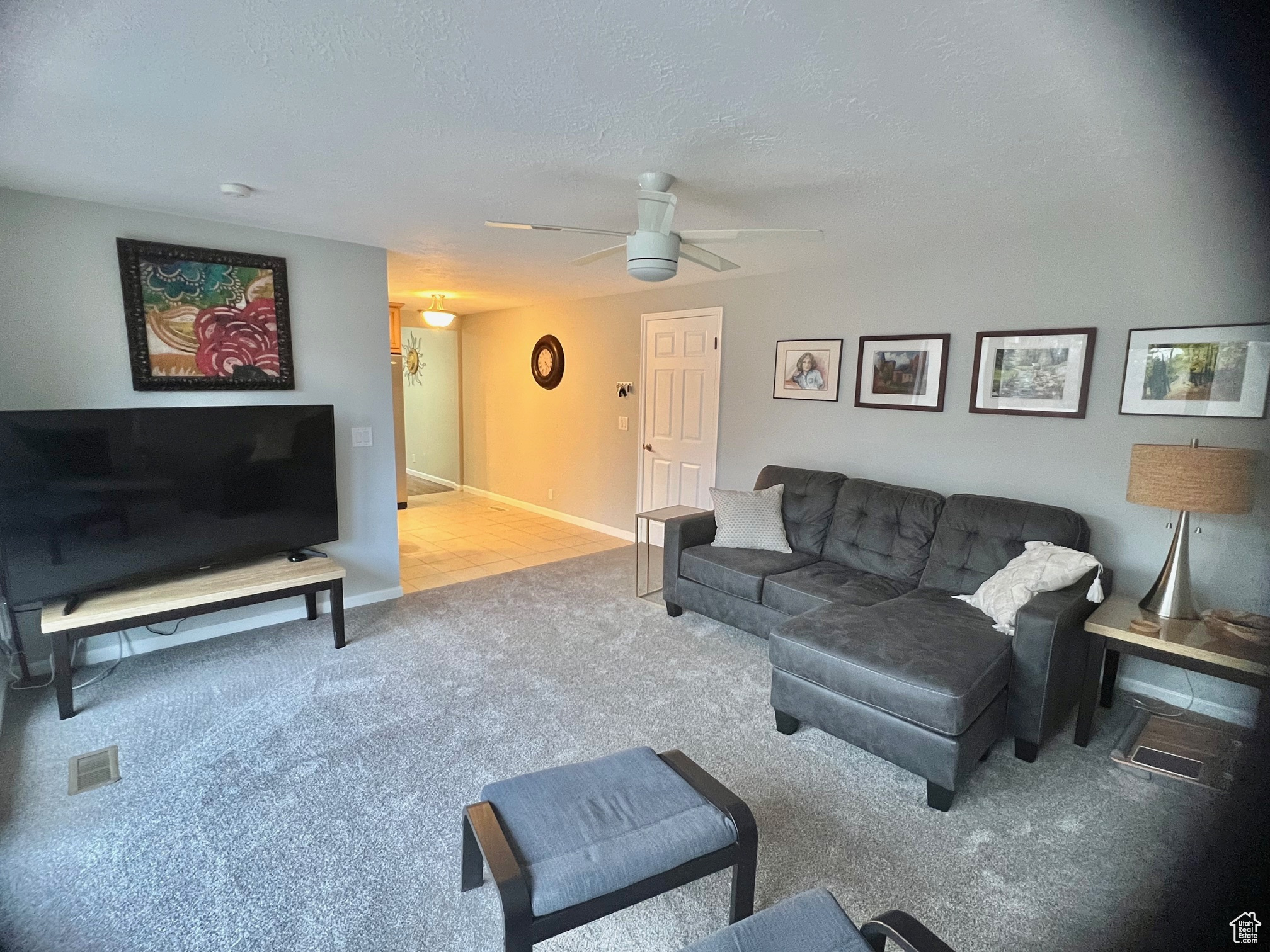 Living room with carpet flooring, ceiling fan, and a textured ceiling