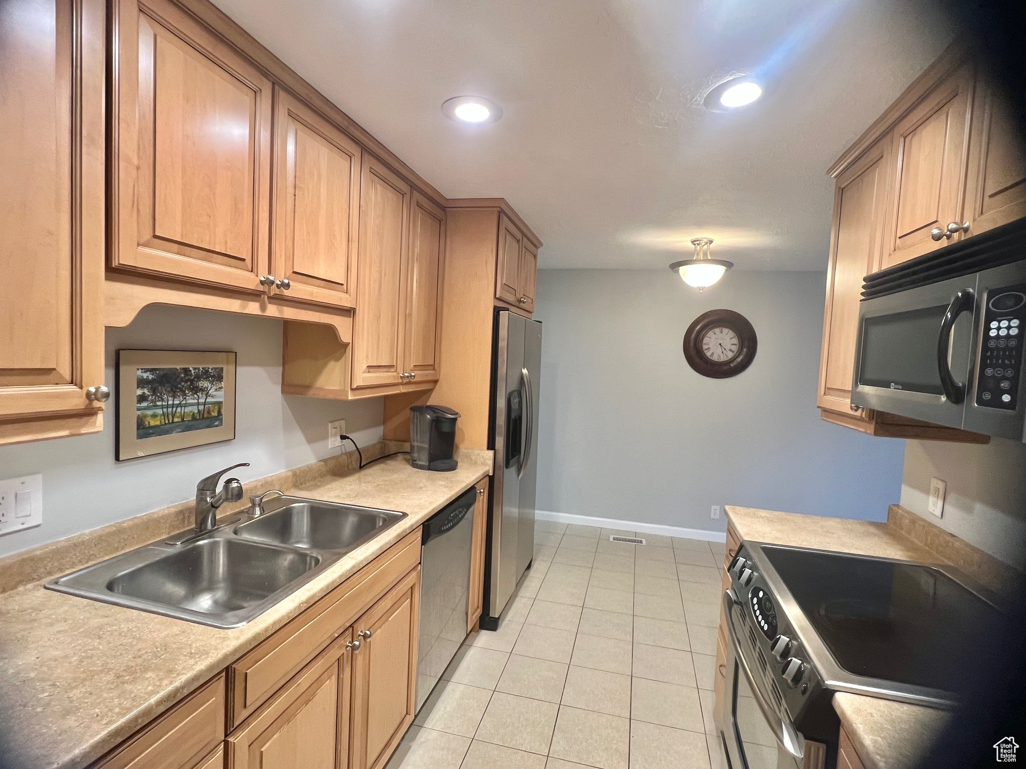 Kitchen featuring sink, light tile patterned floors, and stainless steel appliances