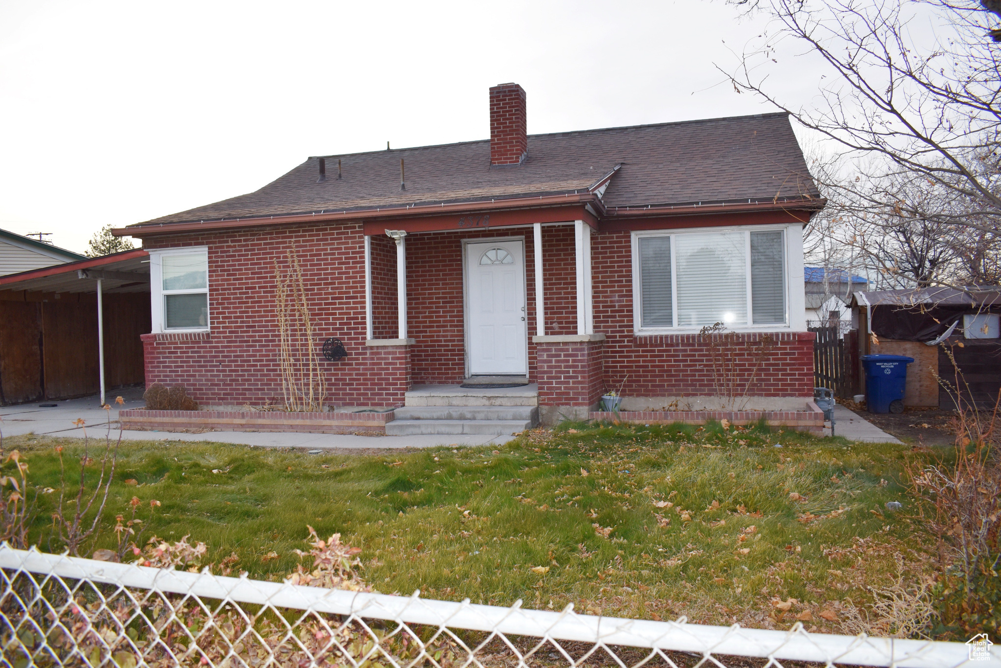 Rear view of property featuring a carport and a lawn