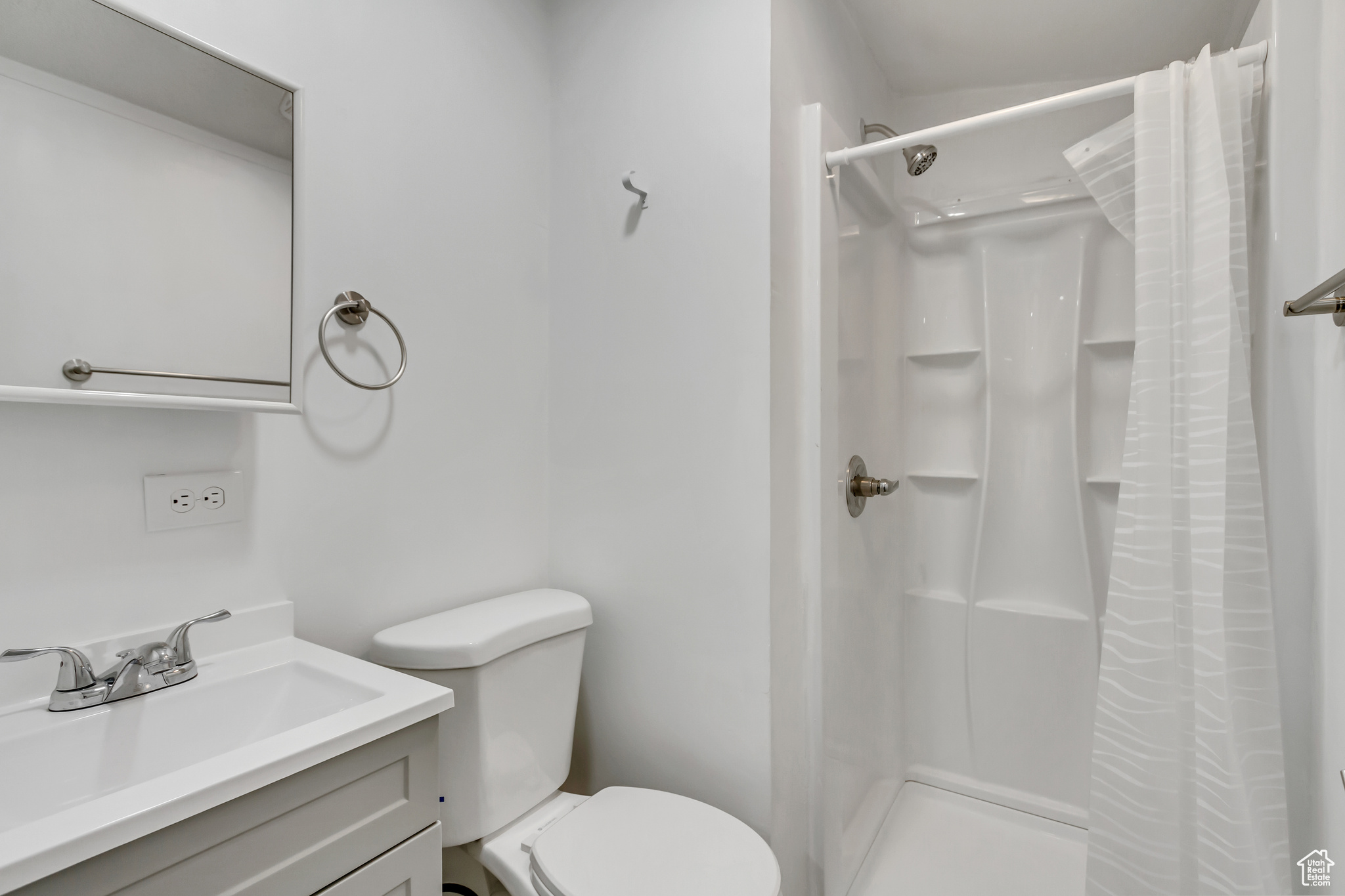 Bathroom featuring a shower with shower curtain, vanity, and toilet