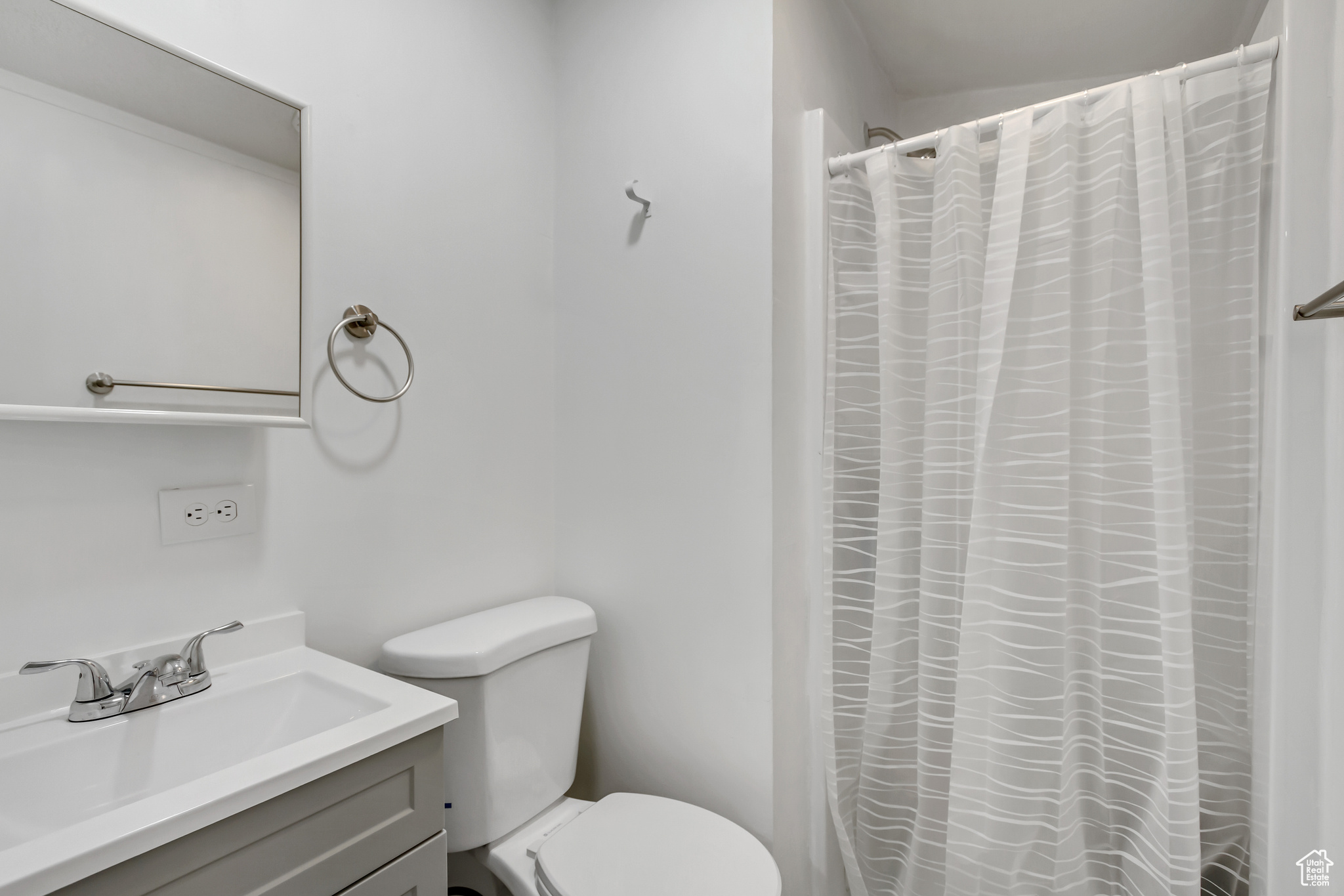 Bathroom featuring vanity, curtained shower, and toilet