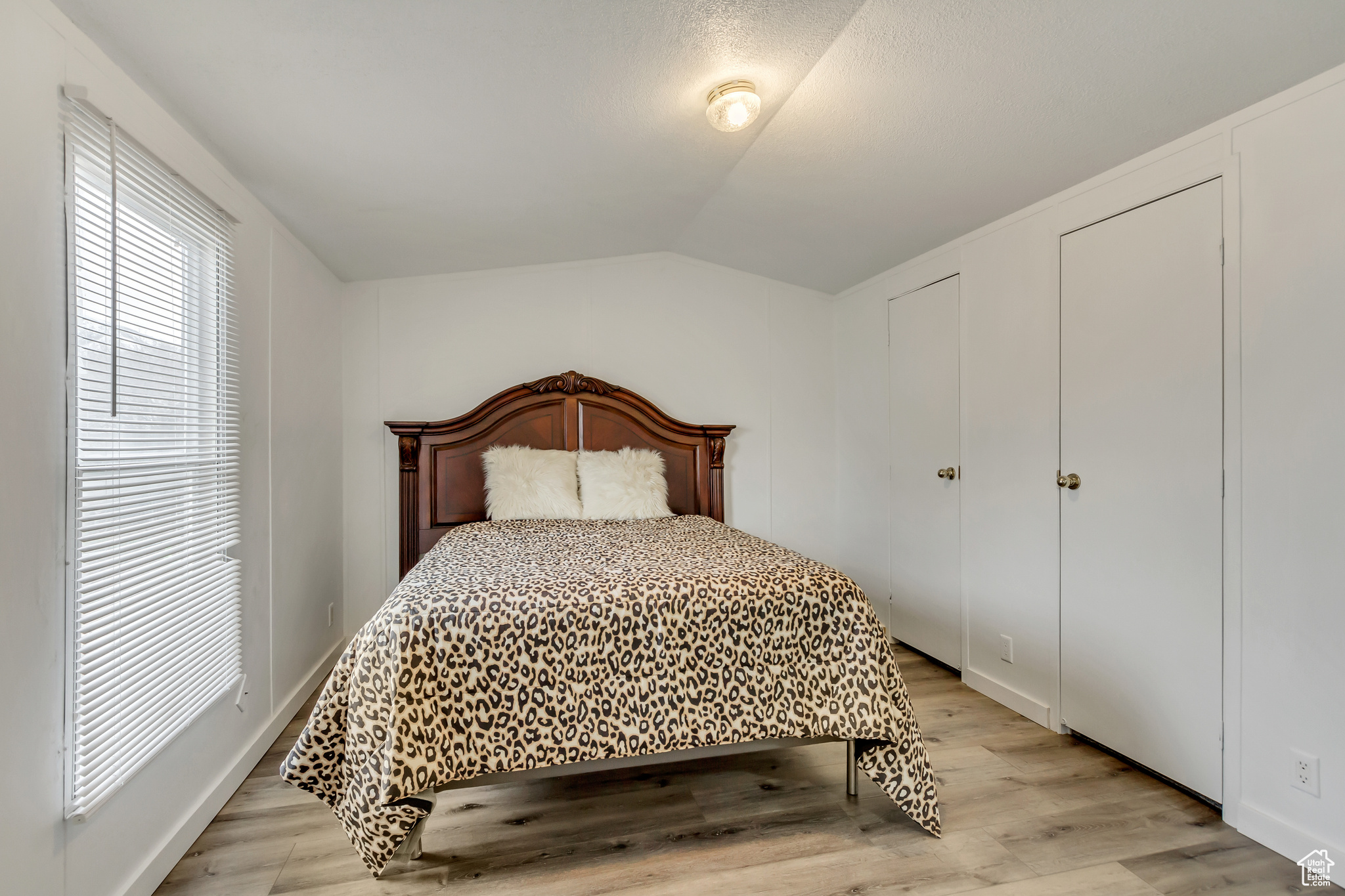 Bedroom with light wood-type flooring and vaulted ceiling