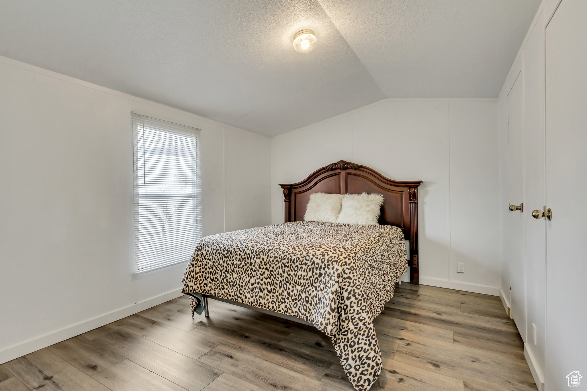 Bedroom featuring light wood-type flooring and vaulted ceiling