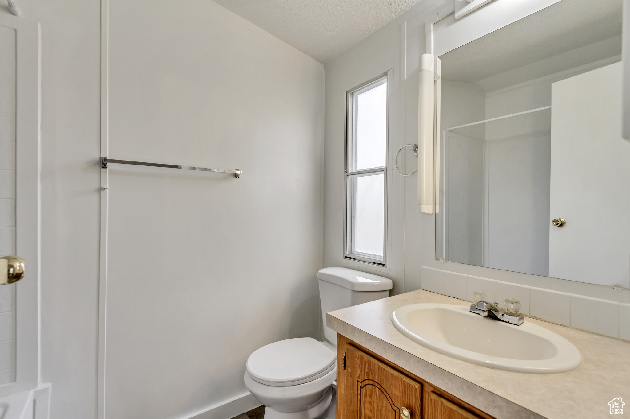 Bathroom with plenty of natural light, toilet, a textured ceiling, and vanity