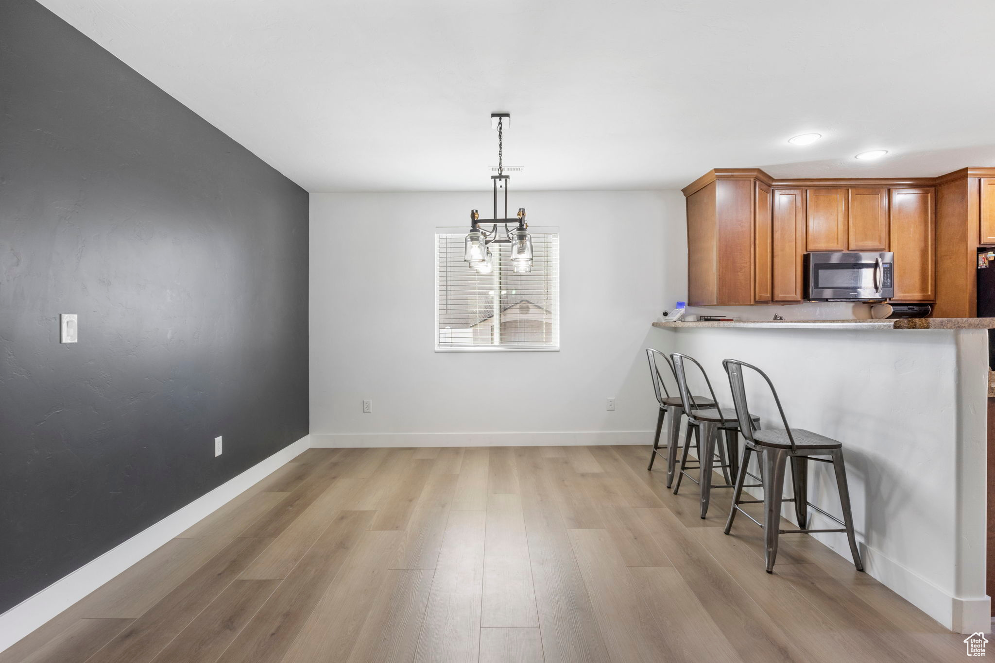 Kitchen with a kitchen breakfast bar, kitchen peninsula, hanging light fixtures, and light hardwood / wood-style flooring