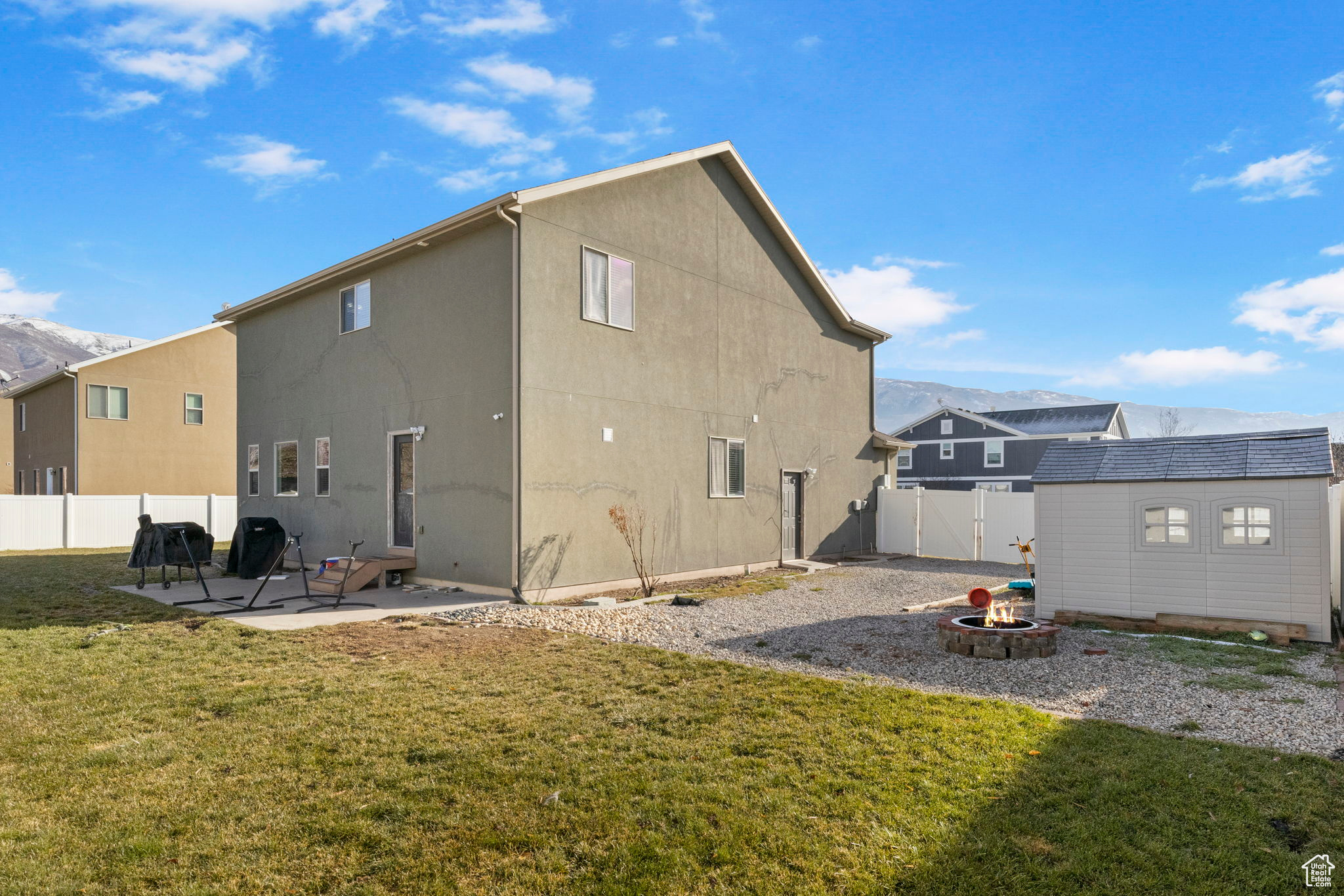 Rear view of house featuring a lawn, a mountain view, a fire pit, a storage shed, and a patio