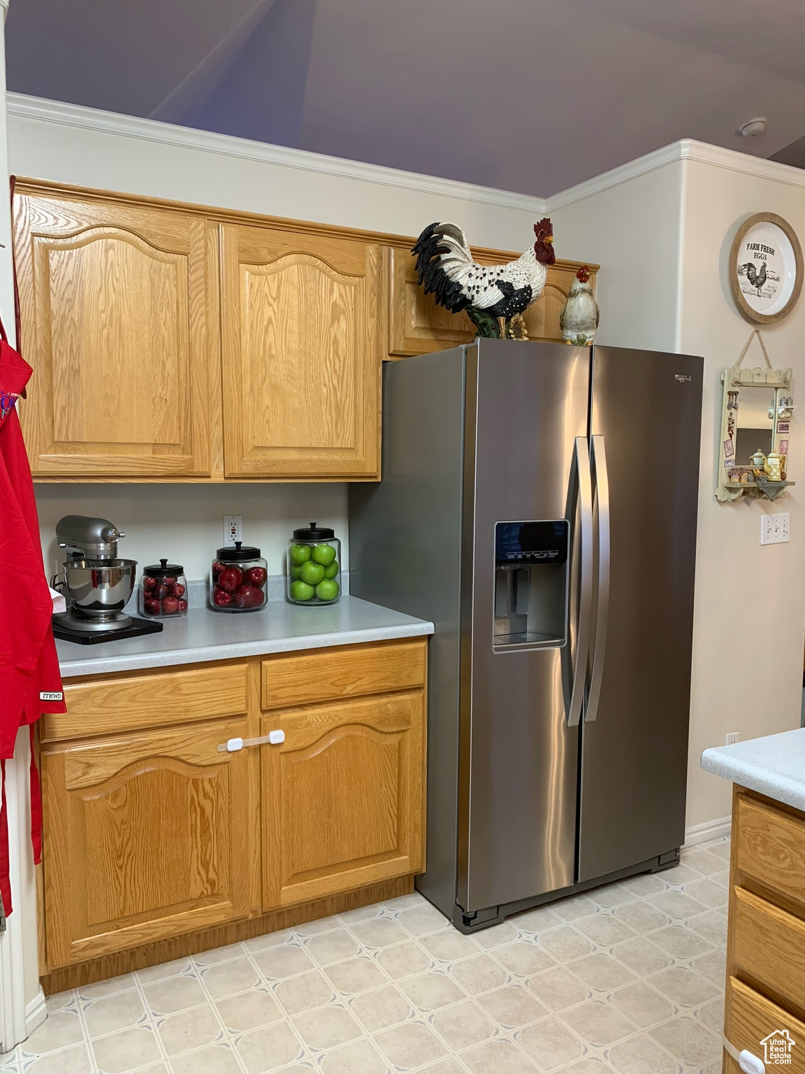 Kitchen featuring ornamental molding and stainless steel refrigerator with ice dispenser