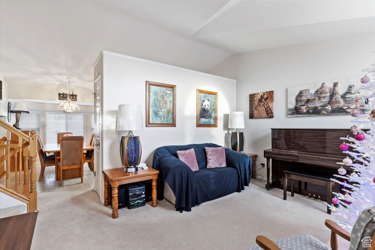 Living room featuring a notable chandelier, light colored carpet, and vaulted ceiling