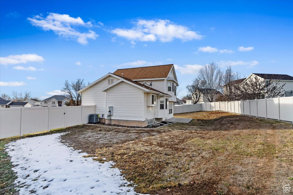 Snow covered rear of property with central air condition unit