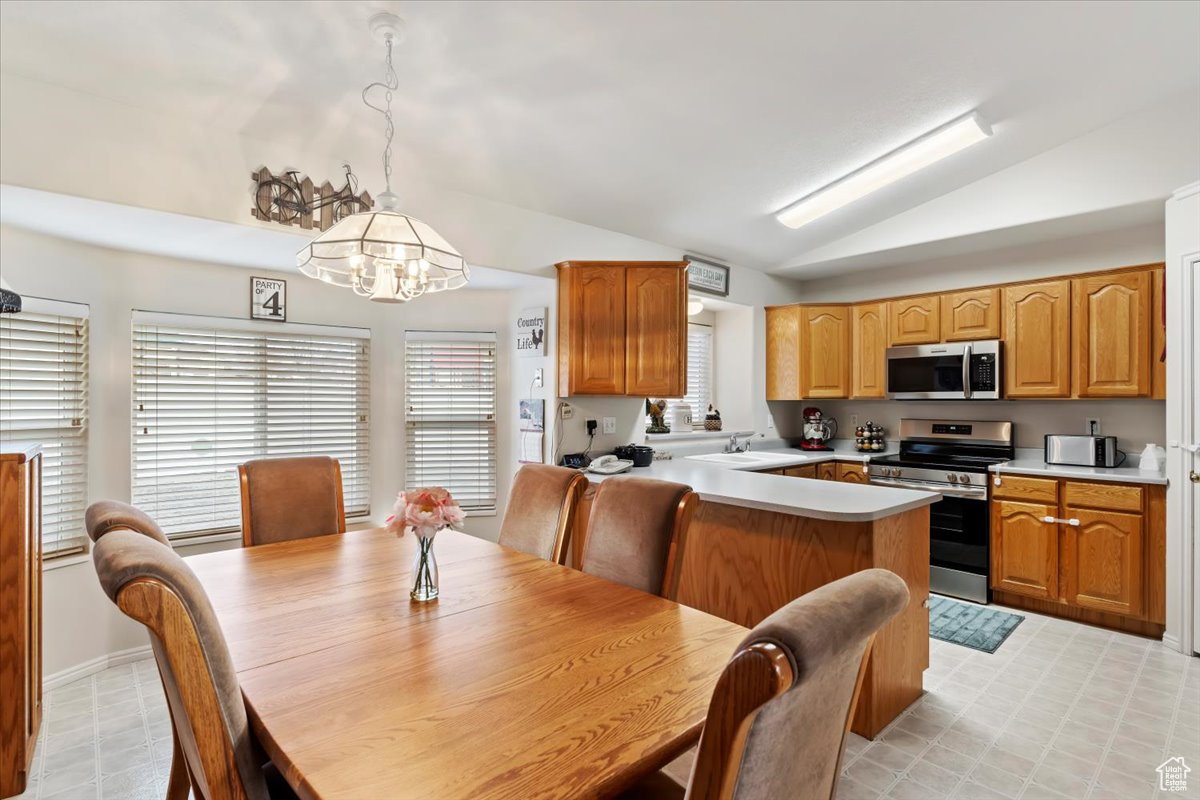 Kitchen featuring appliances with stainless steel finishes, hanging light fixtures, lofted ceiling, and a notable chandelier