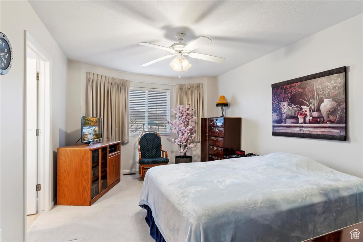 Carpeted bedroom featuring ceiling fan