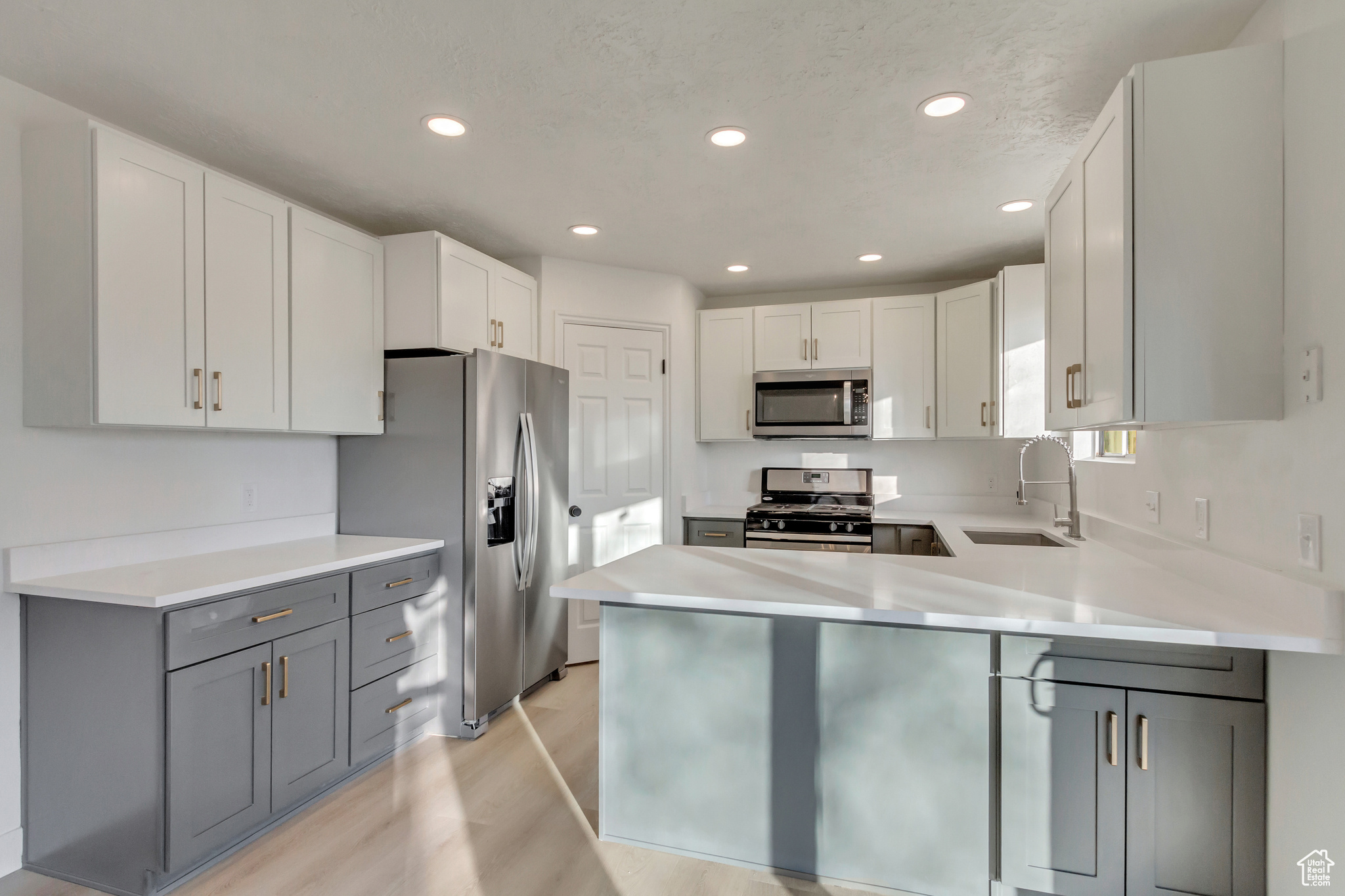 Kitchen featuring sink, white cabinets, appliances with stainless steel finishes, and gray cabinetry