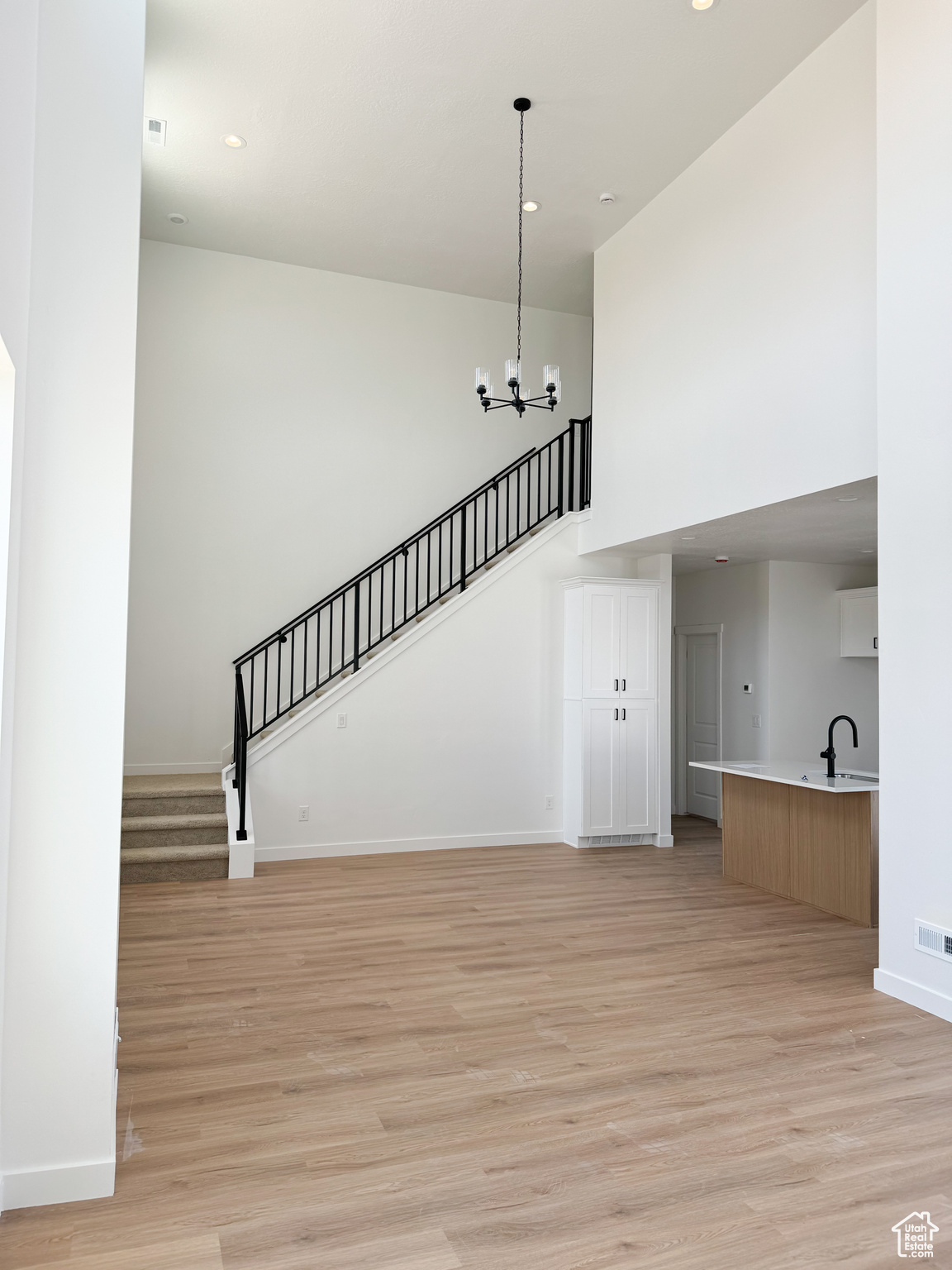 Unfurnished living room featuring an inviting chandelier, sink, and light hardwood / wood-style flooring