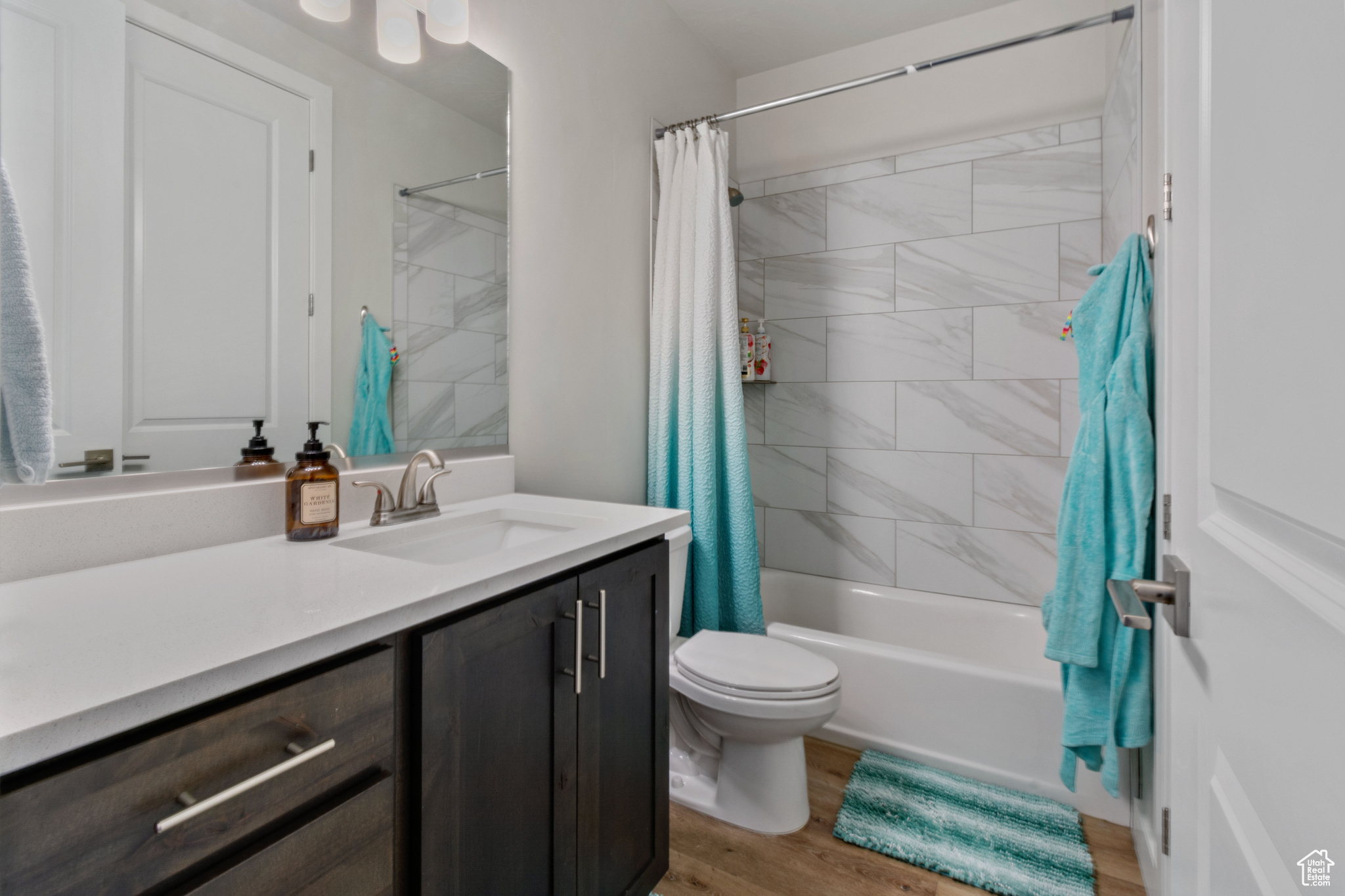 Full bathroom with wood-type flooring, vanity, shower / tub combo, and toilet