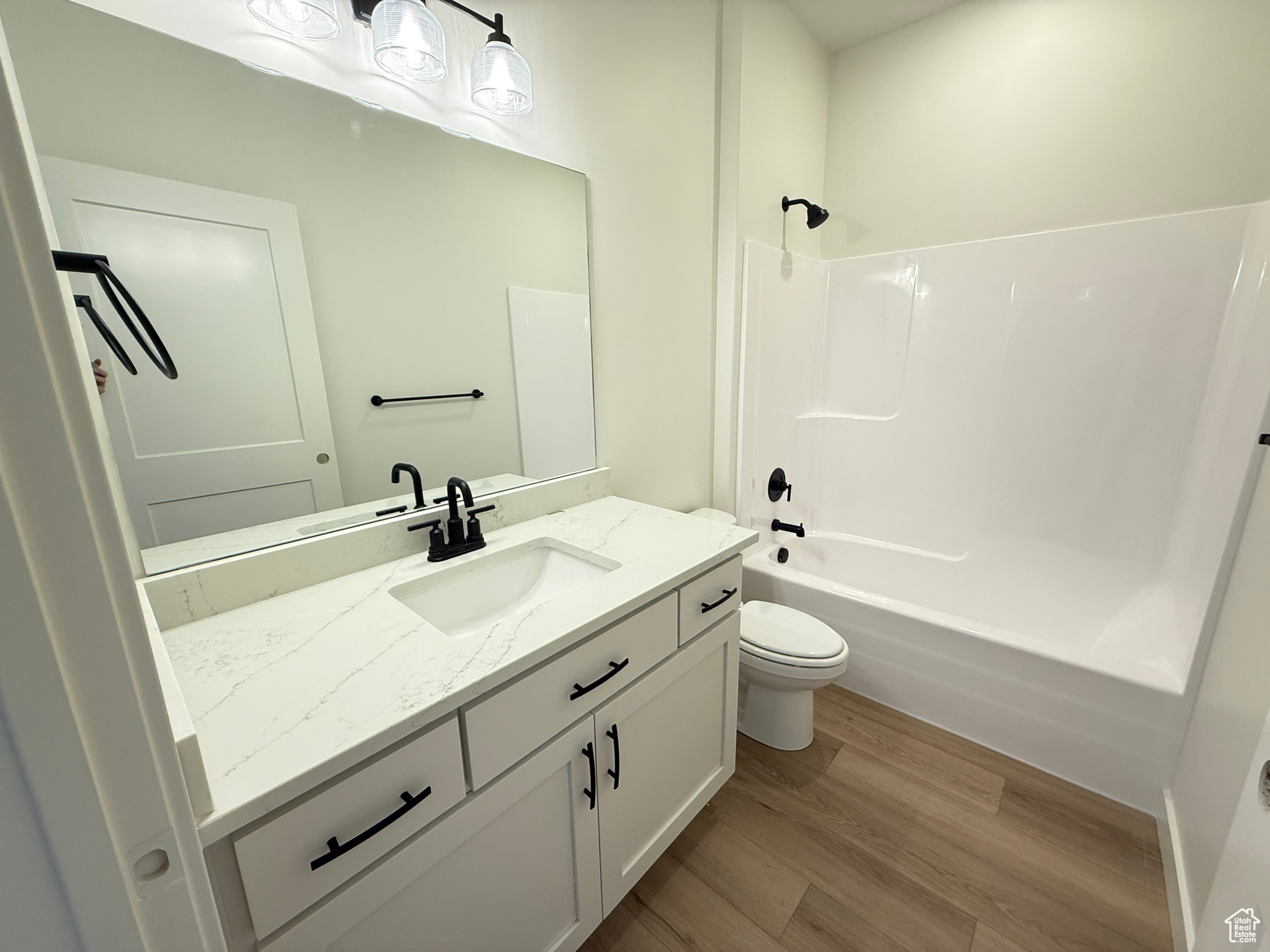 Full bathroom featuring shower / bath combination, vanity, wood-type flooring, and toilet