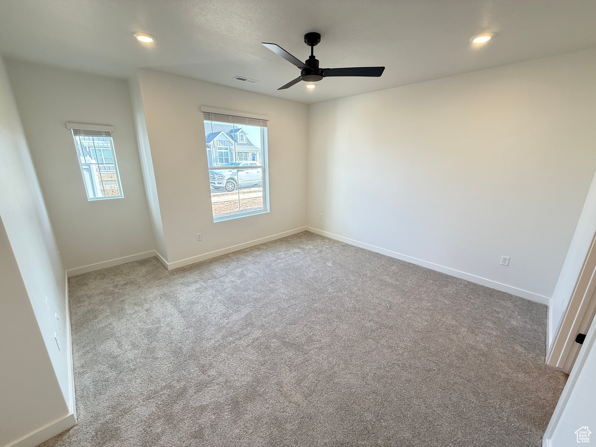 Unfurnished room with ceiling fan, plenty of natural light, and light colored carpet