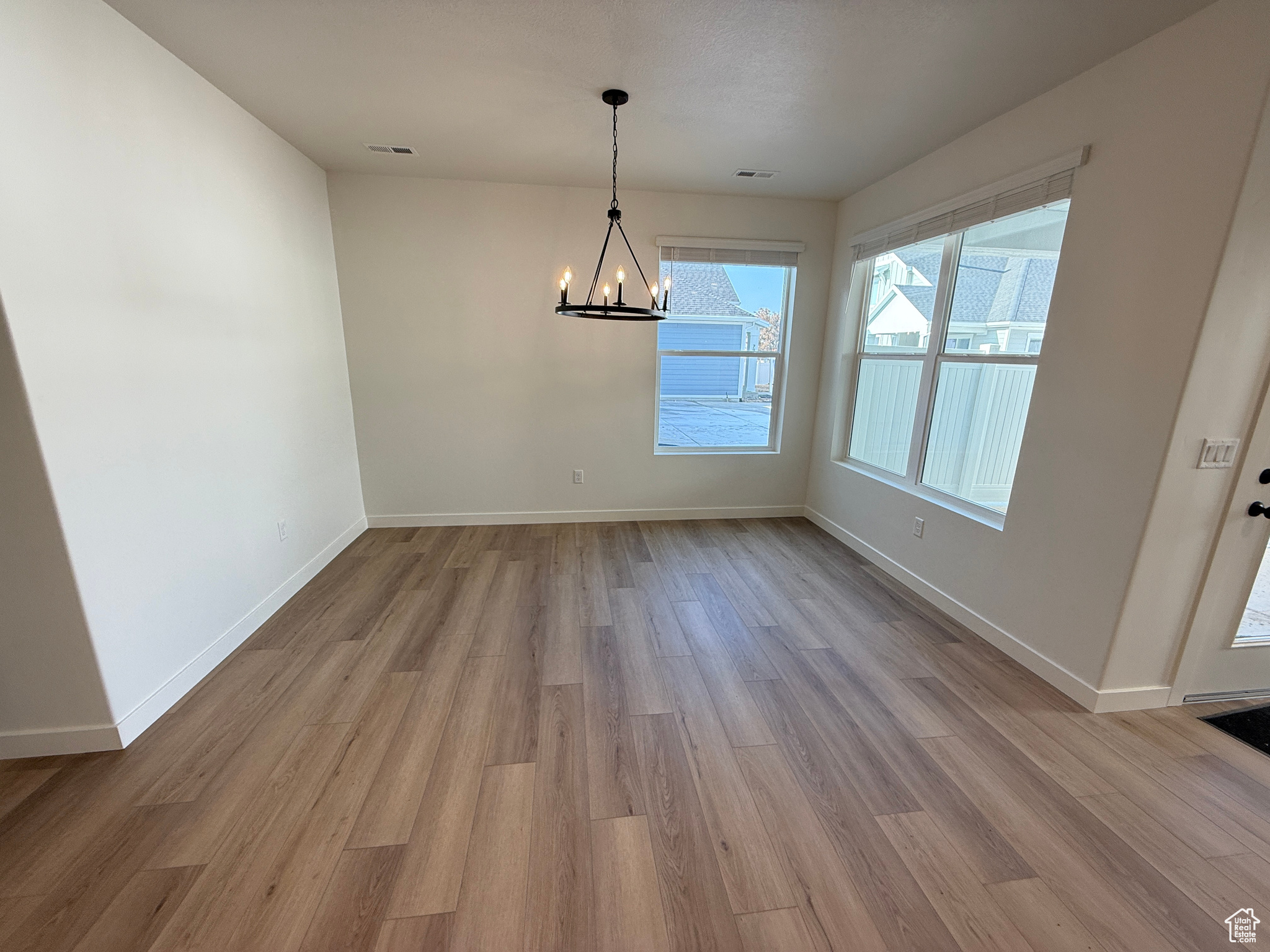 Unfurnished dining area with light wood-type flooring and an inviting chandelier