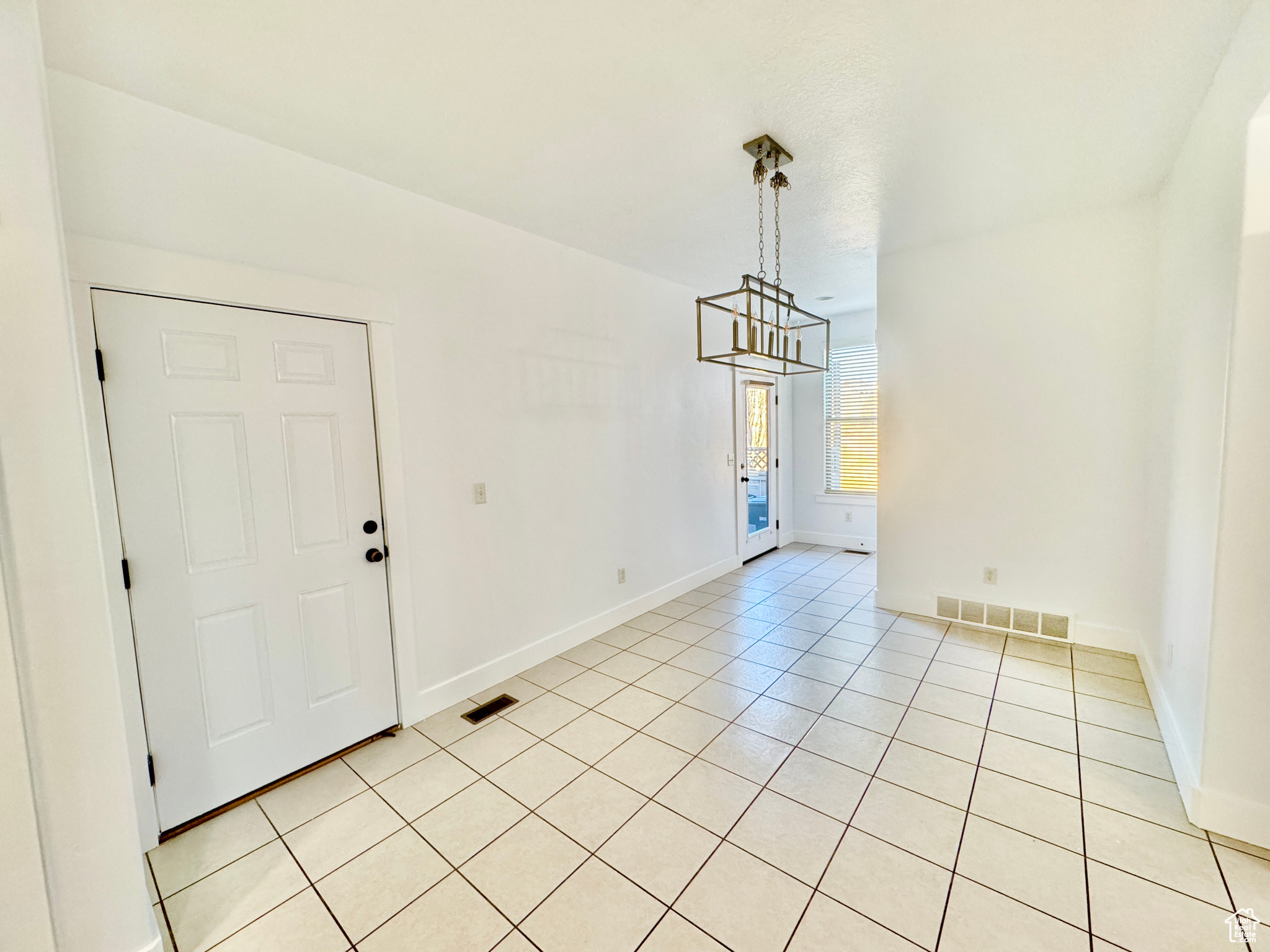 Unfurnished dining area with a notable chandelier and light tile patterned flooring