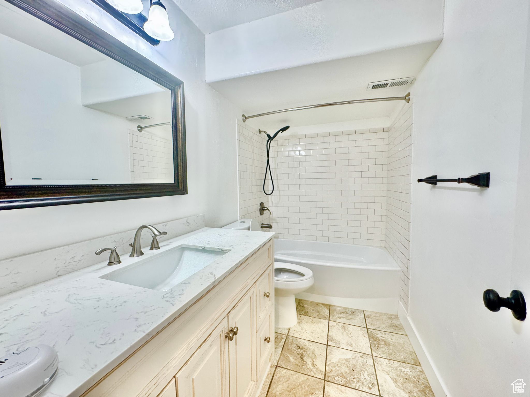 Full bathroom featuring tile patterned floors, vanity, toilet, and tiled shower / bath combo